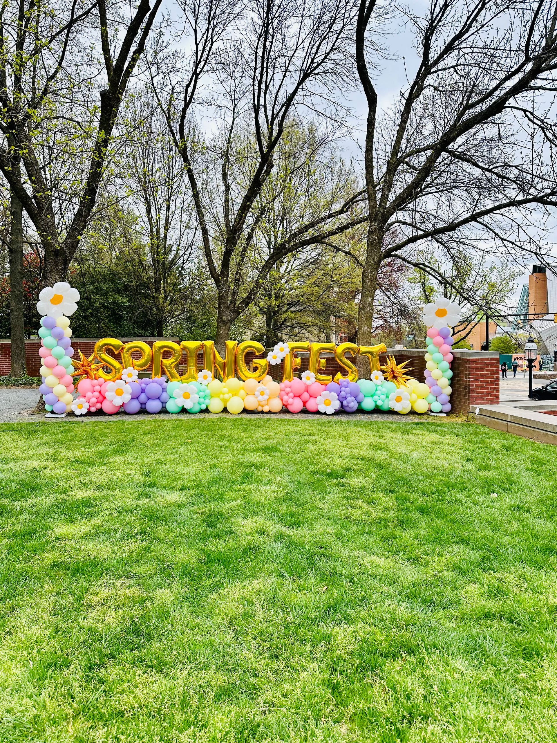 A large sign made of balloons and flowers is sitting on top of a lush green field.
