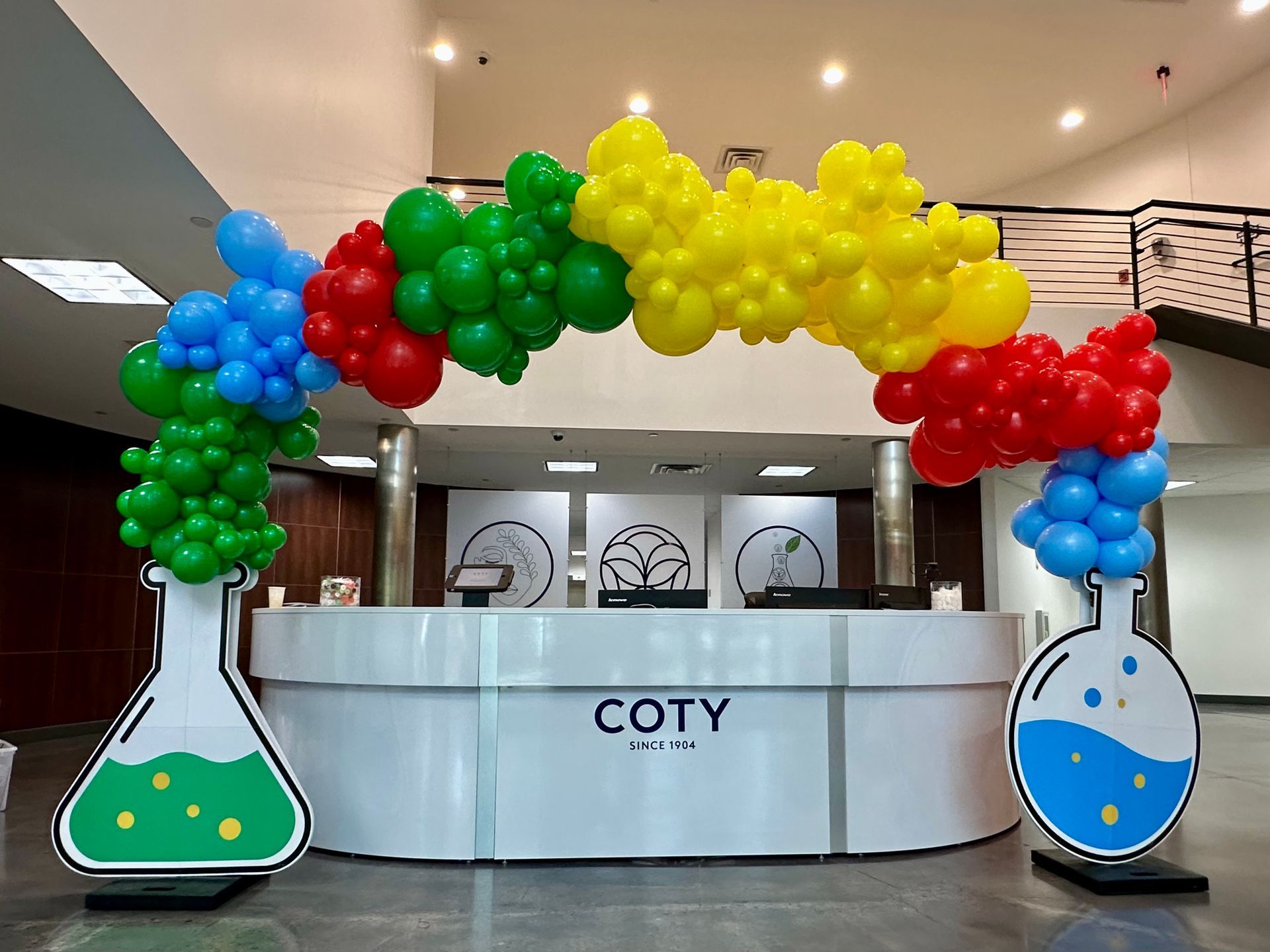 A reception desk is decorated with balloons and a balloon arch.