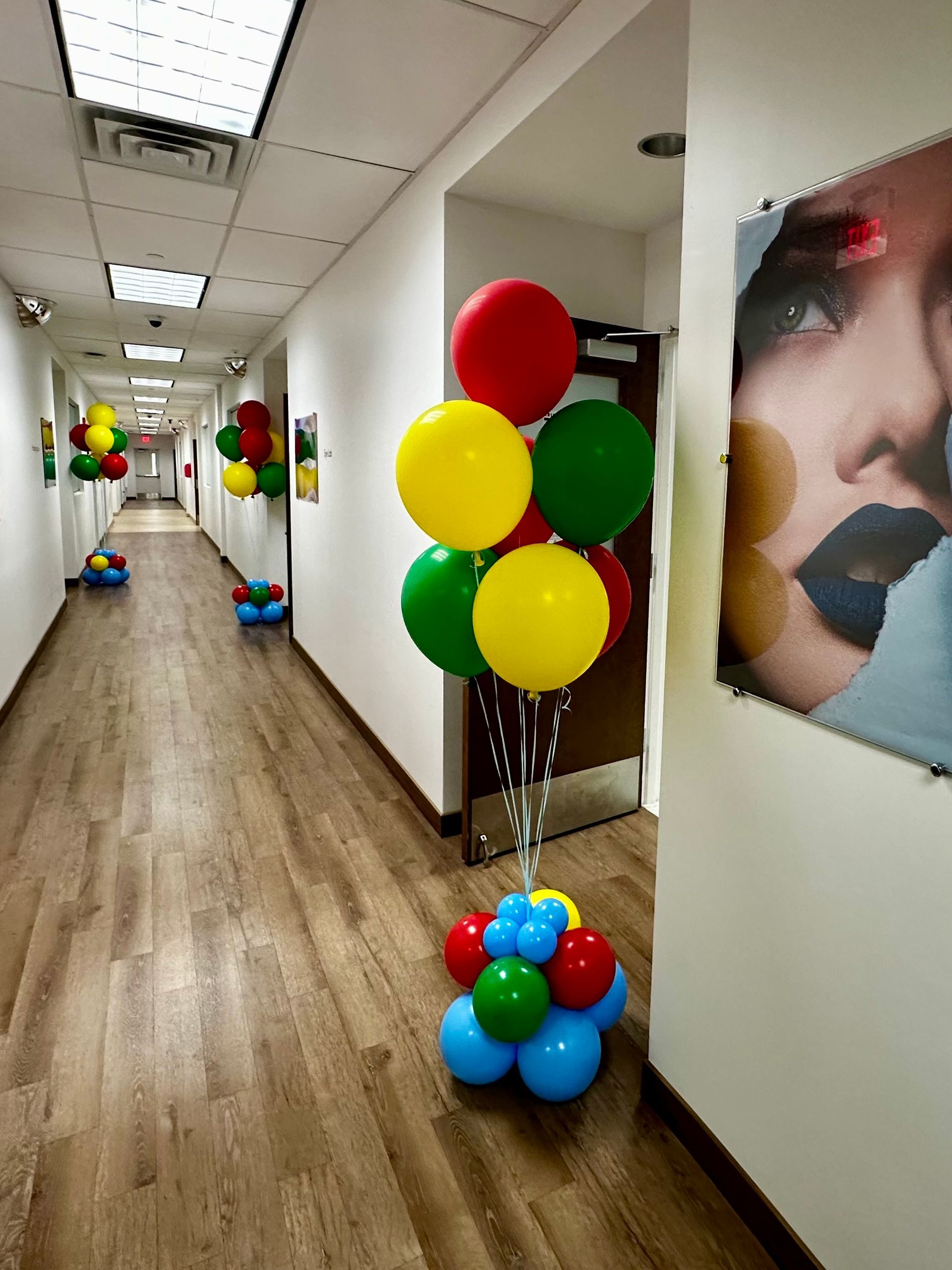 A bunch of balloons in a hallway next to a picture of a woman 's face