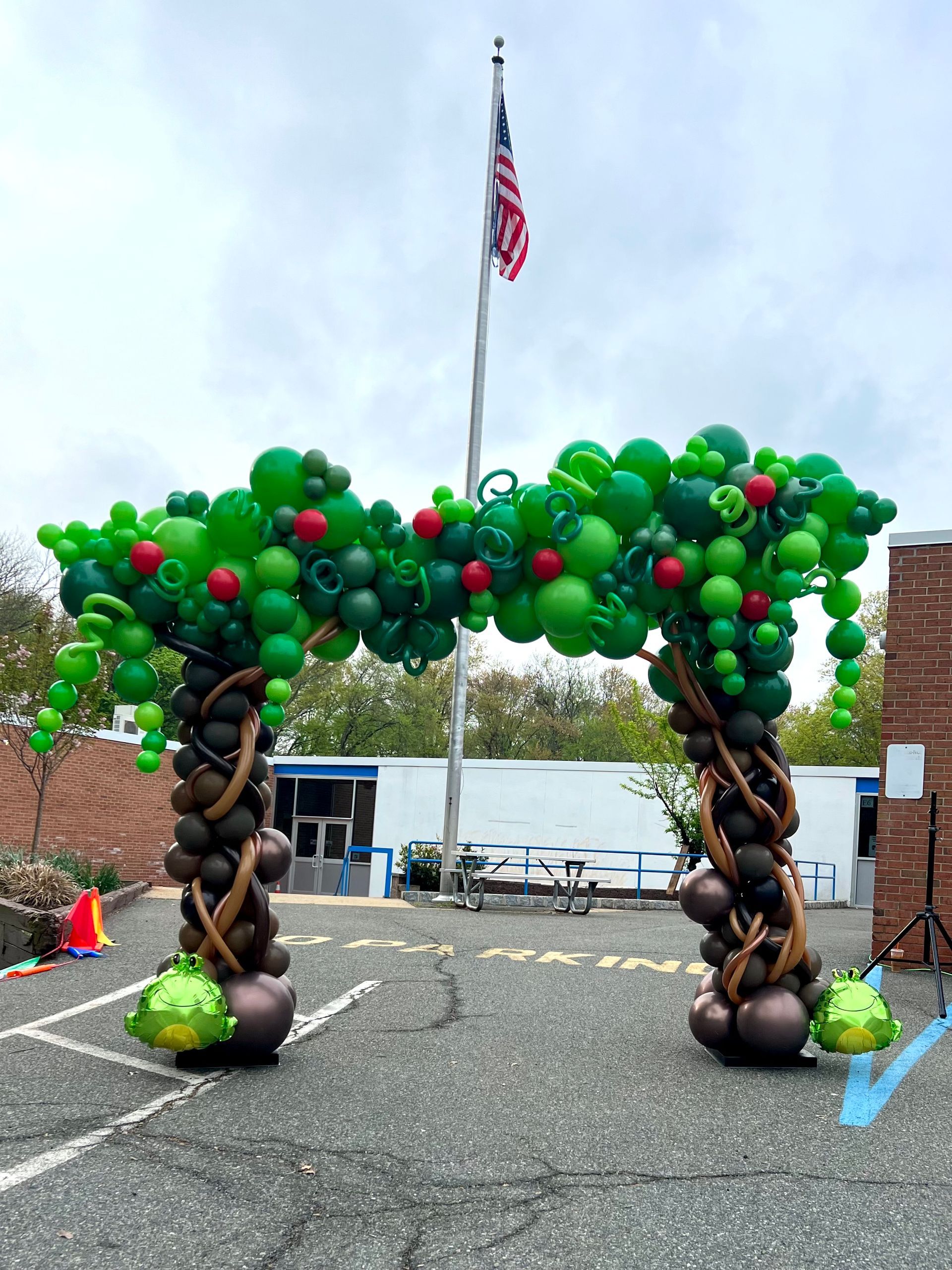 A balloon arch in the shape of an apple tree with a flag in the background.