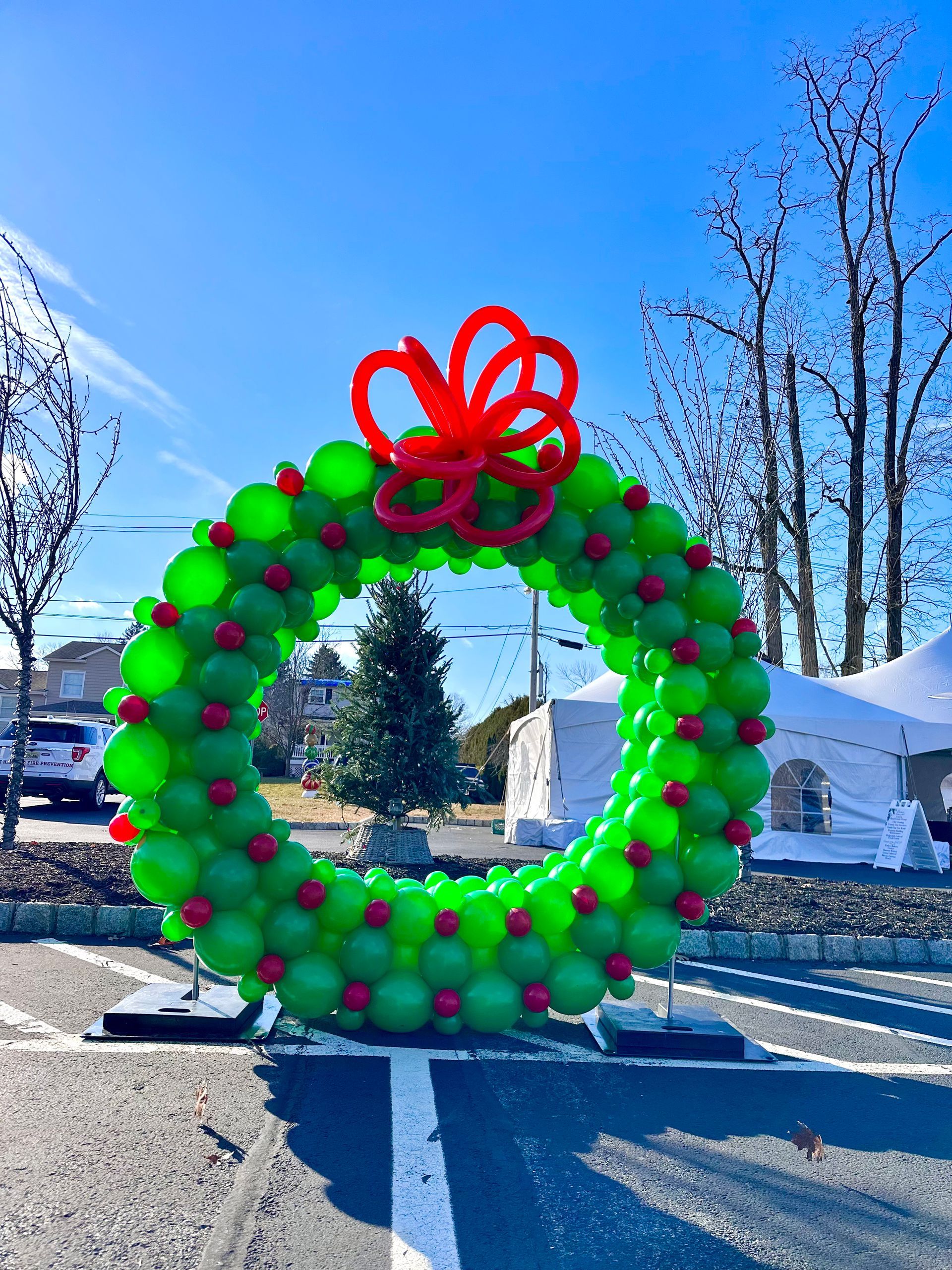A christmas wreath made of green balloons with a red bow