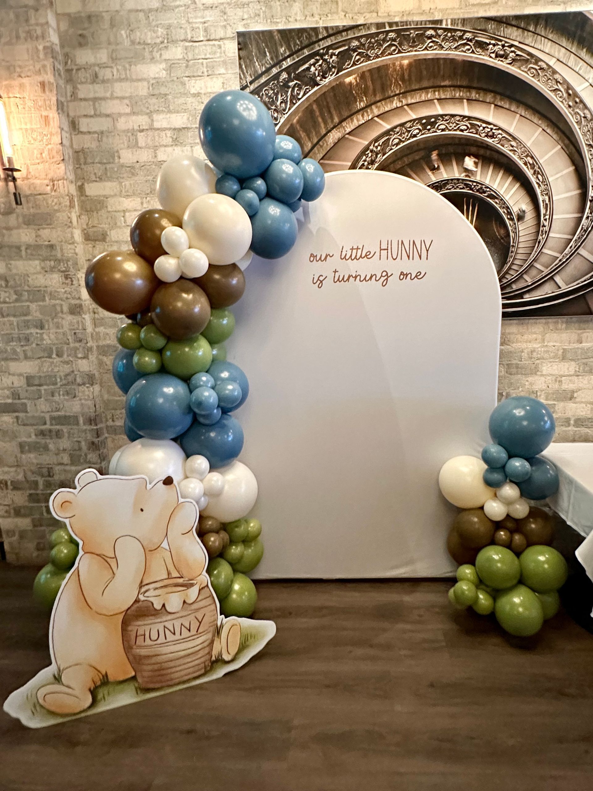 A baby shower backdrop with balloons and a winnie the pooh cutout.