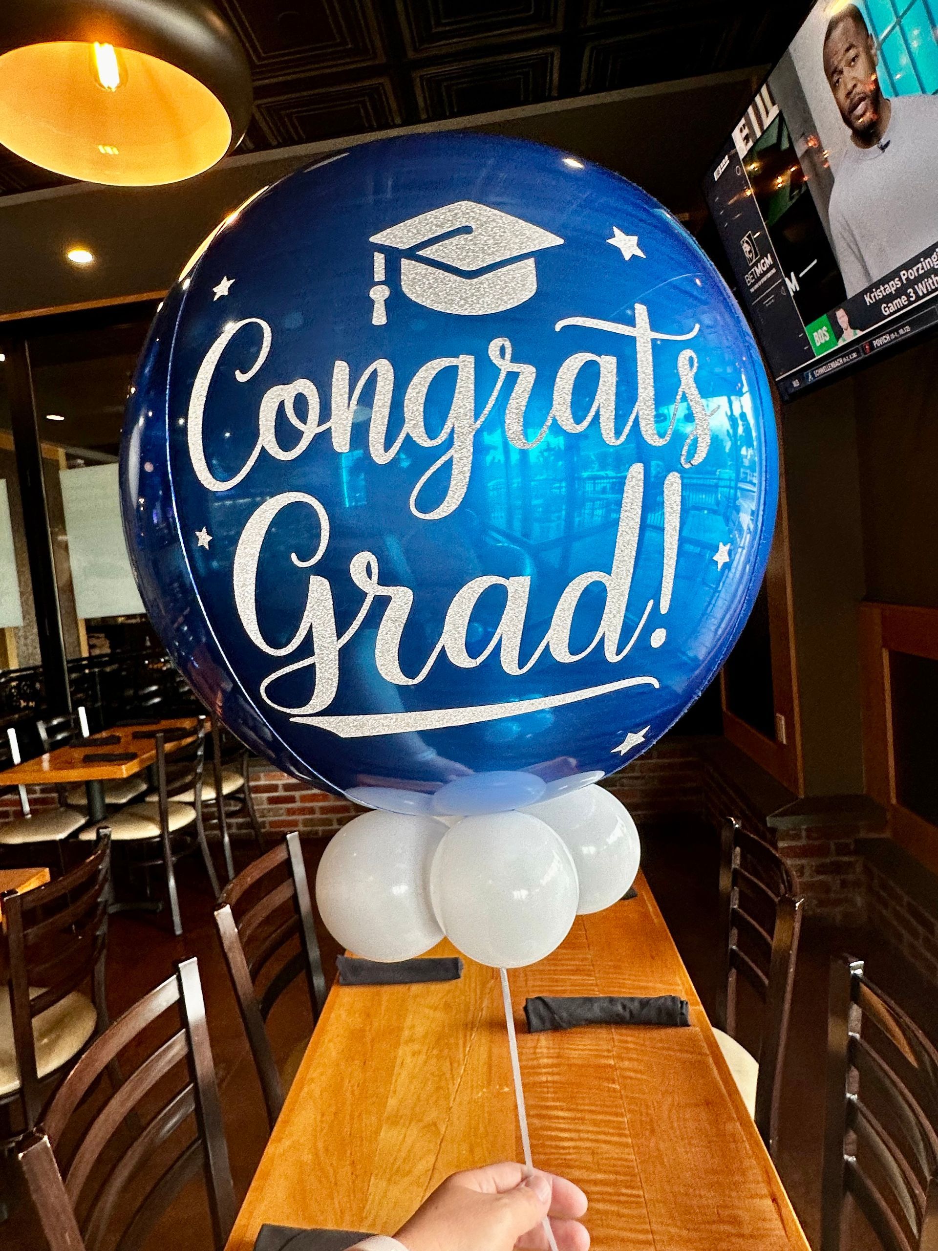 A congratulations grad balloon is sitting on a table in a restaurant.
