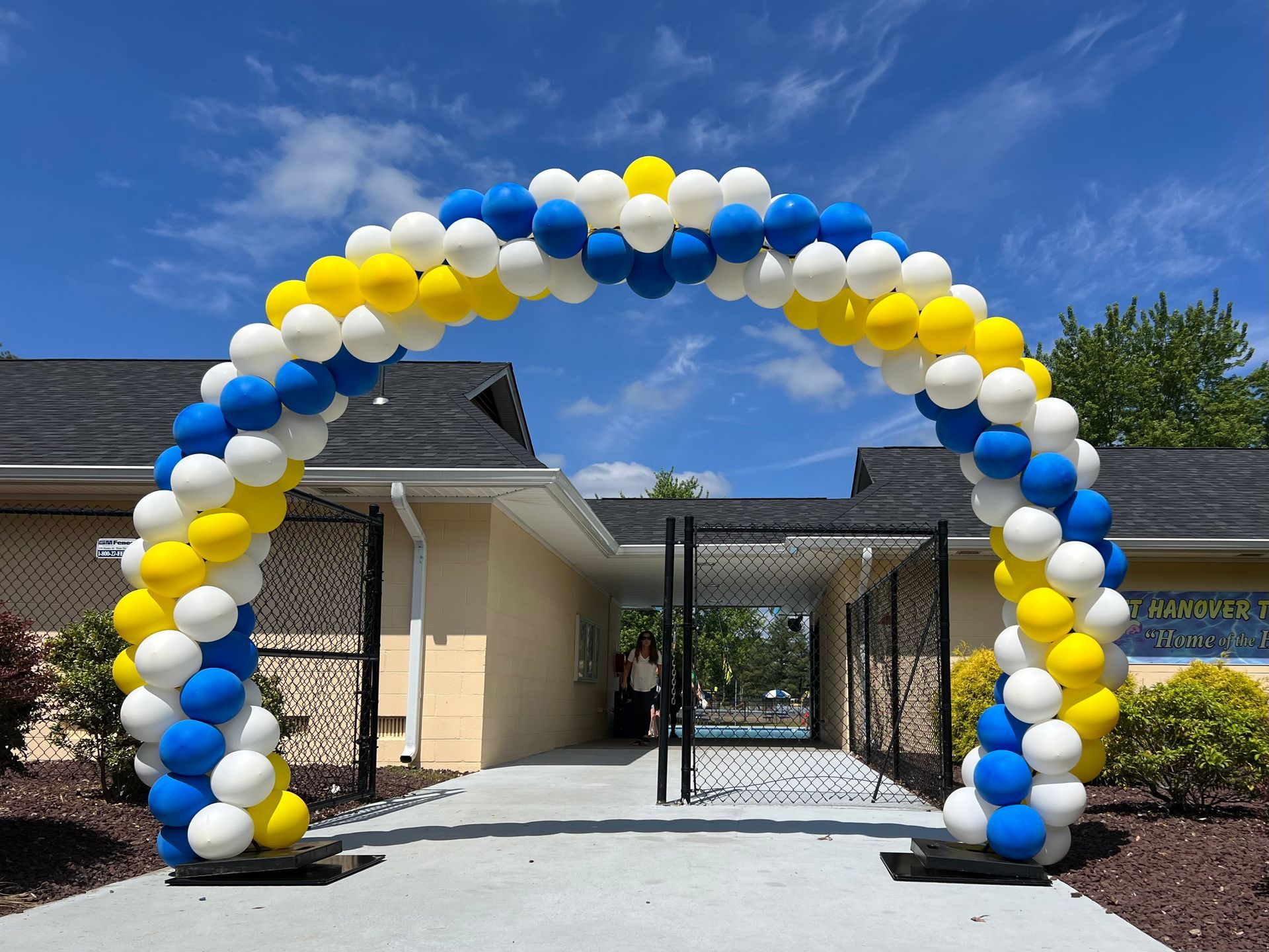 A blue , yellow and white balloon arch in front of a building