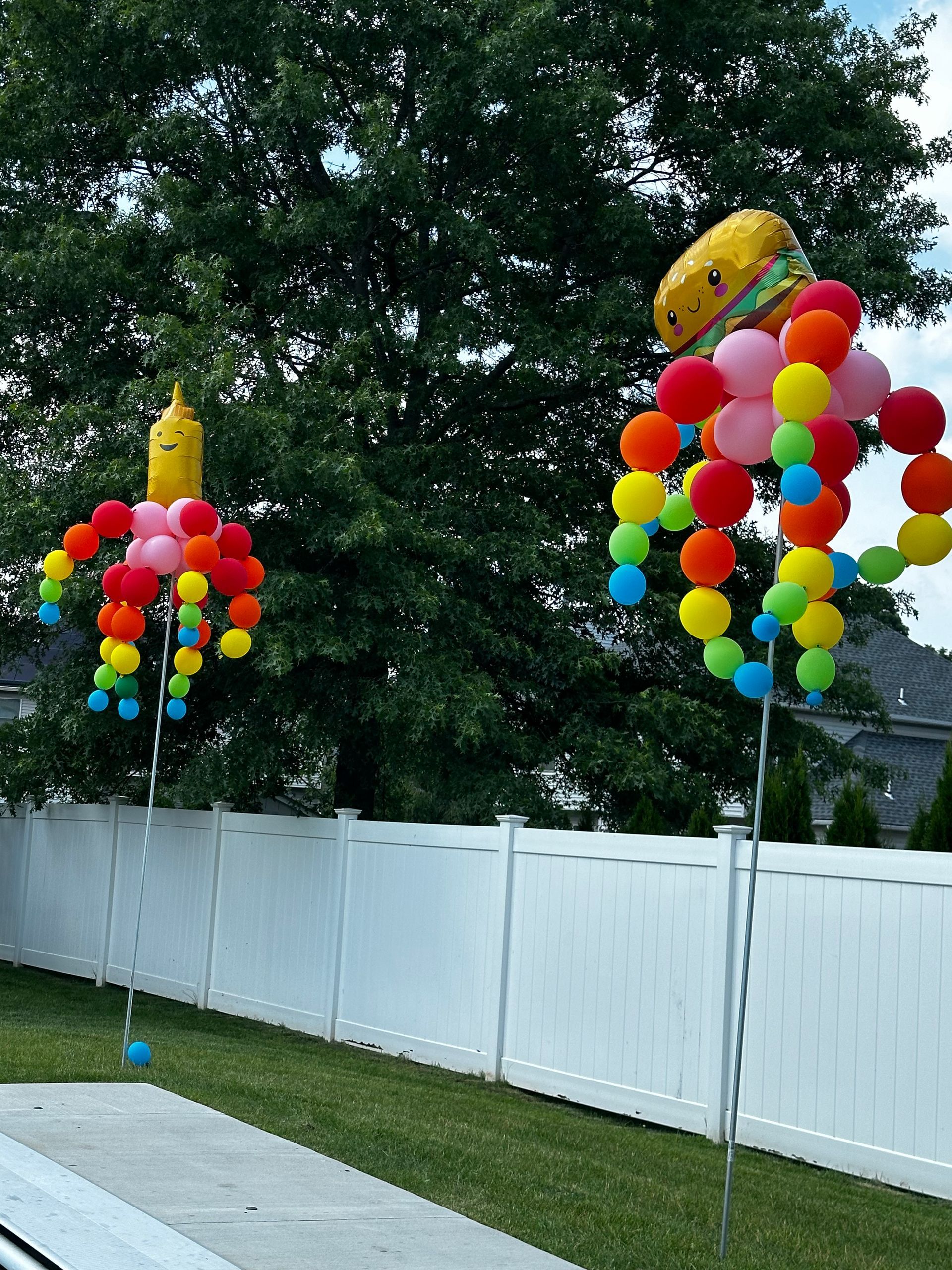 A bunch of balloons in the shape of a bottle and a hamburger