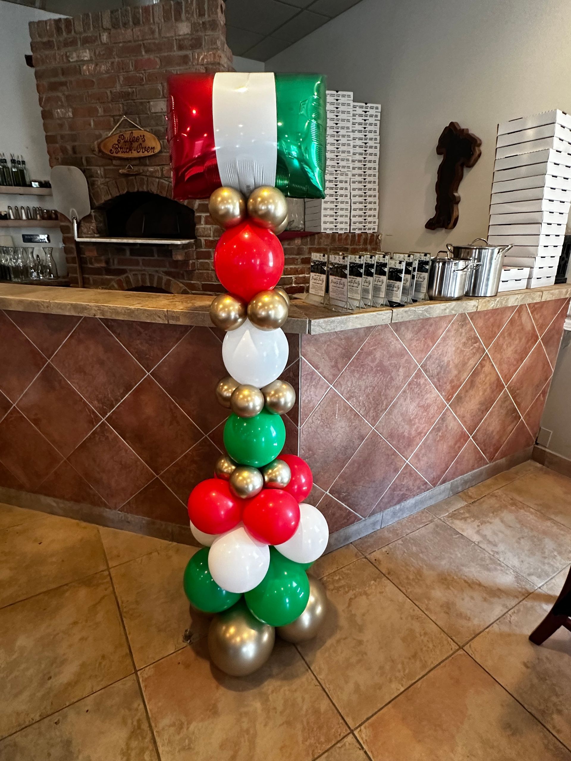 A column of red , green , and gold balloons in a restaurant.