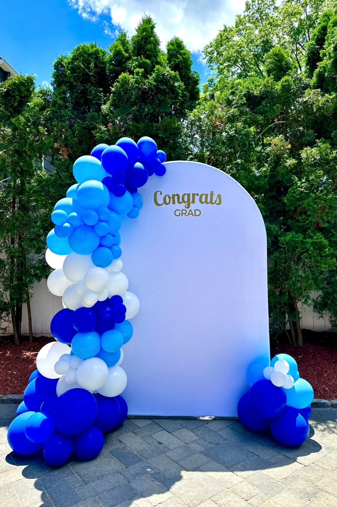 A white wall surrounded by blue and white balloons.