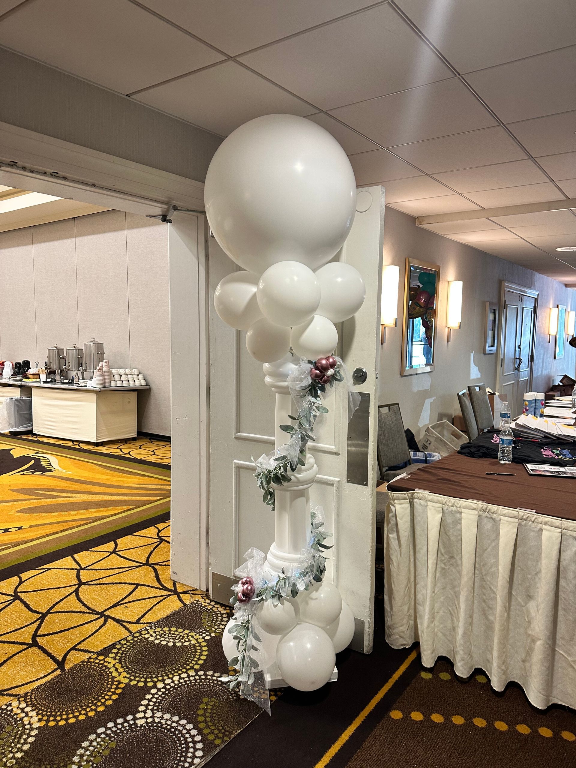 A room with a bunch of white balloons on a pedestal