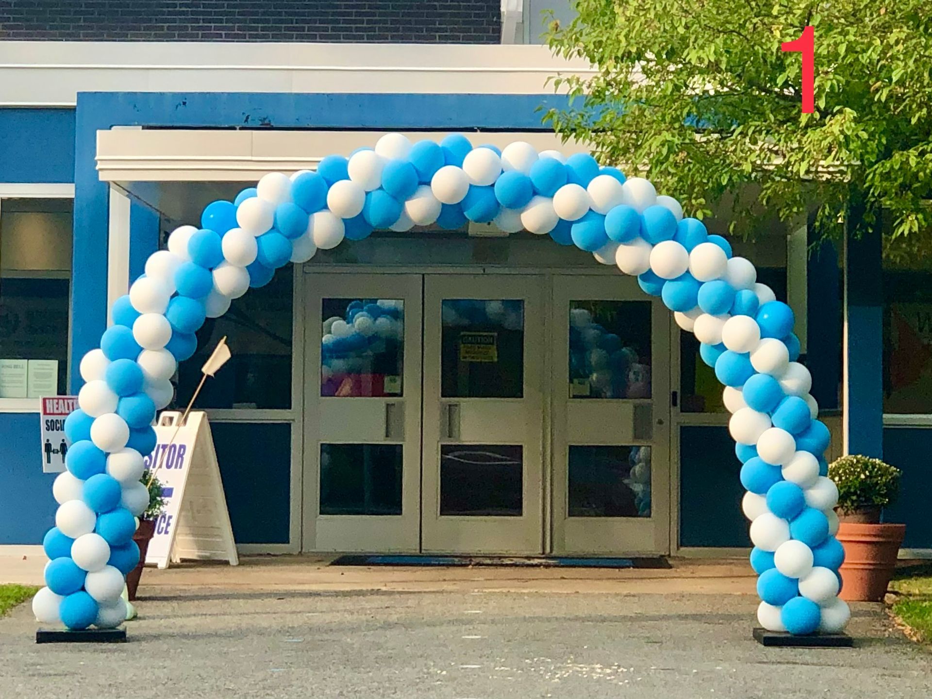 A blue and white balloon arch in front of a building