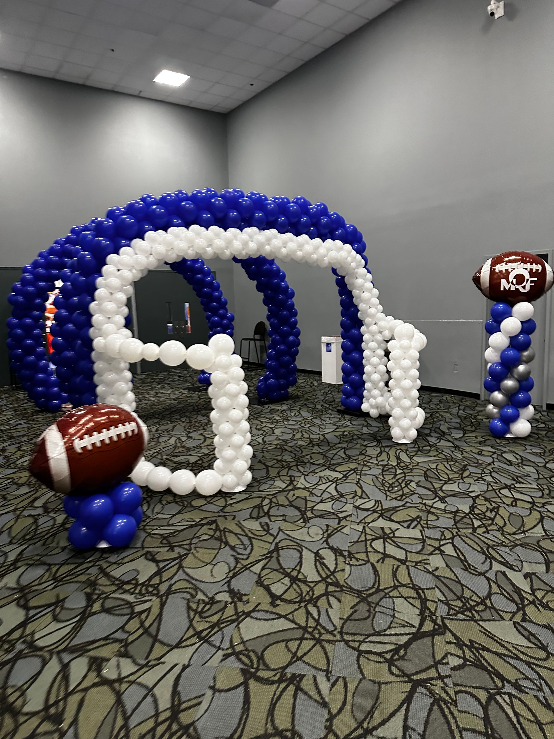 A room decorated with blue and white balloons and a football