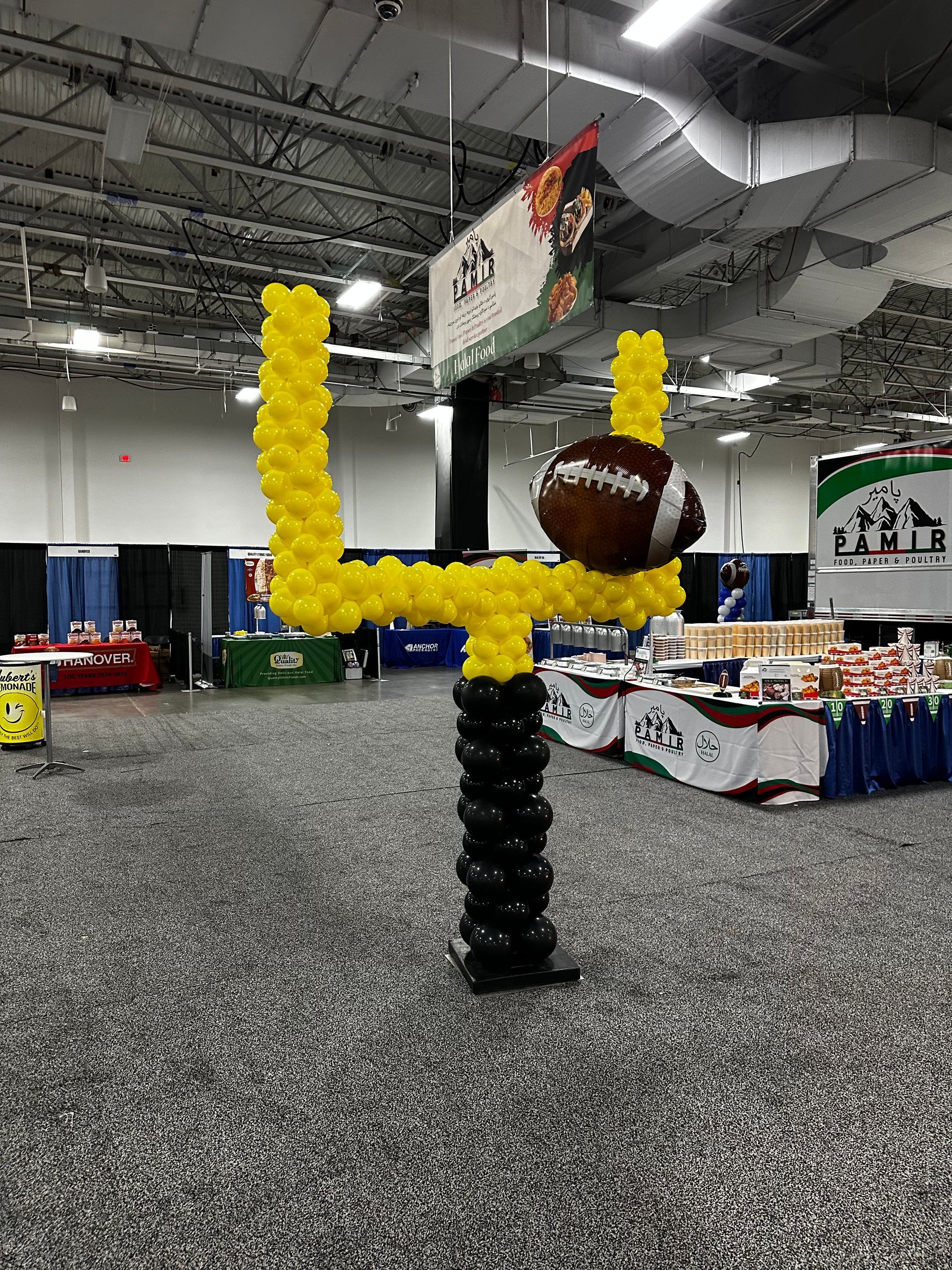A football is sitting on top of a goal post made of balloons.