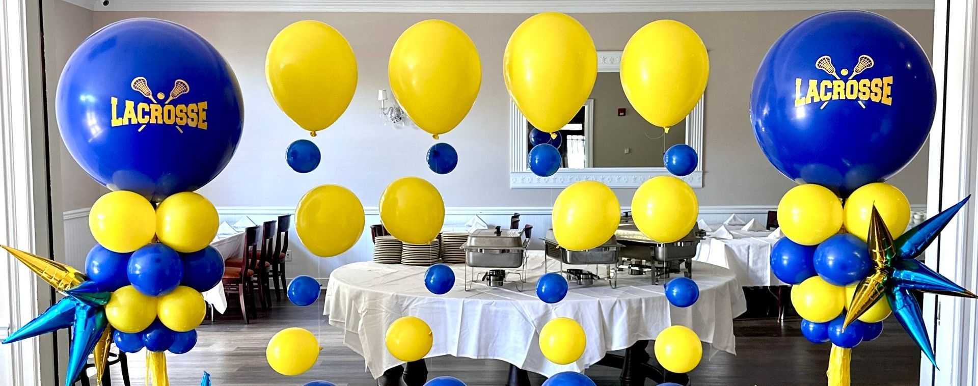 A room decorated with blue and yellow balloons and a table.