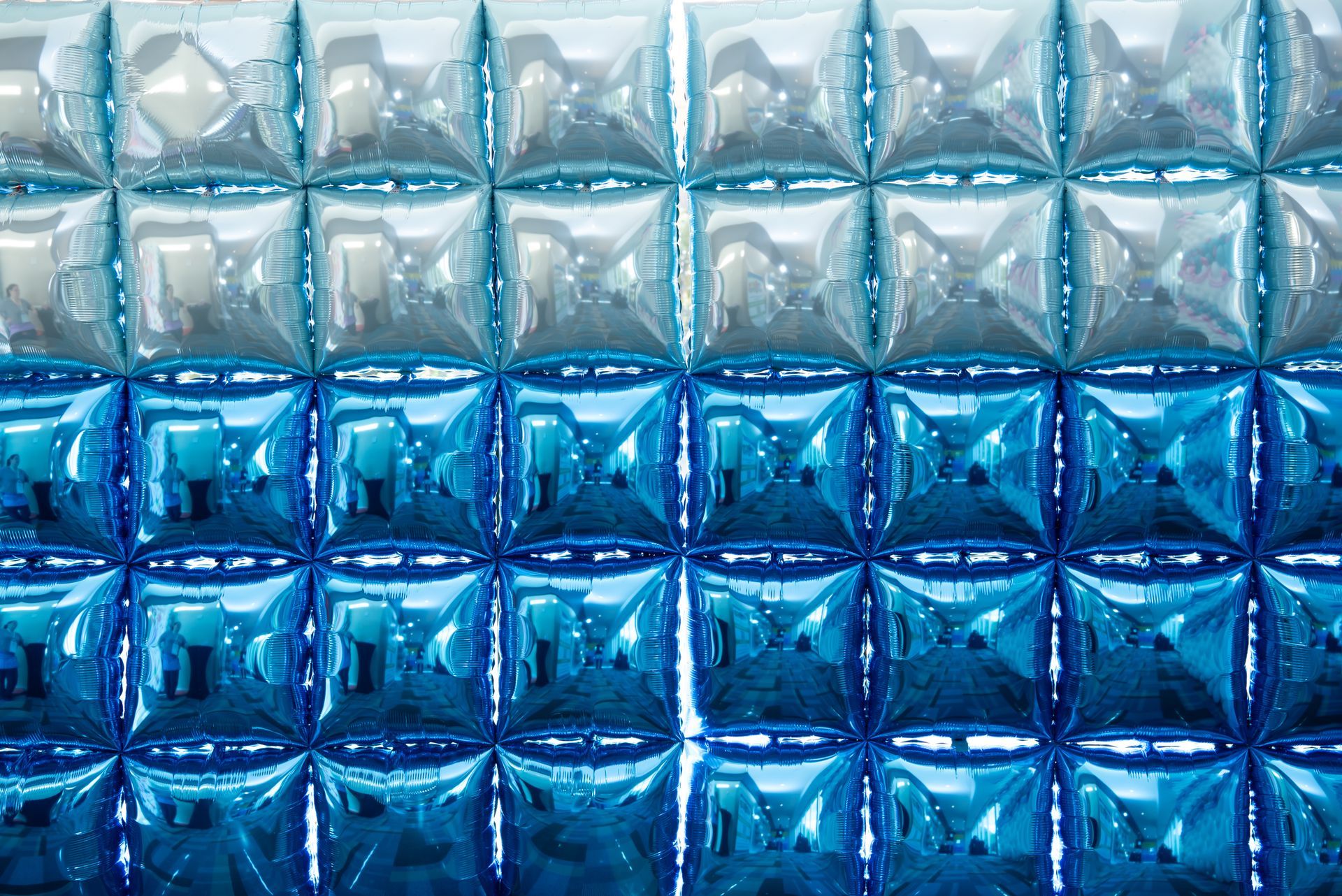 A close up of a wall made of blue and silver balloons.