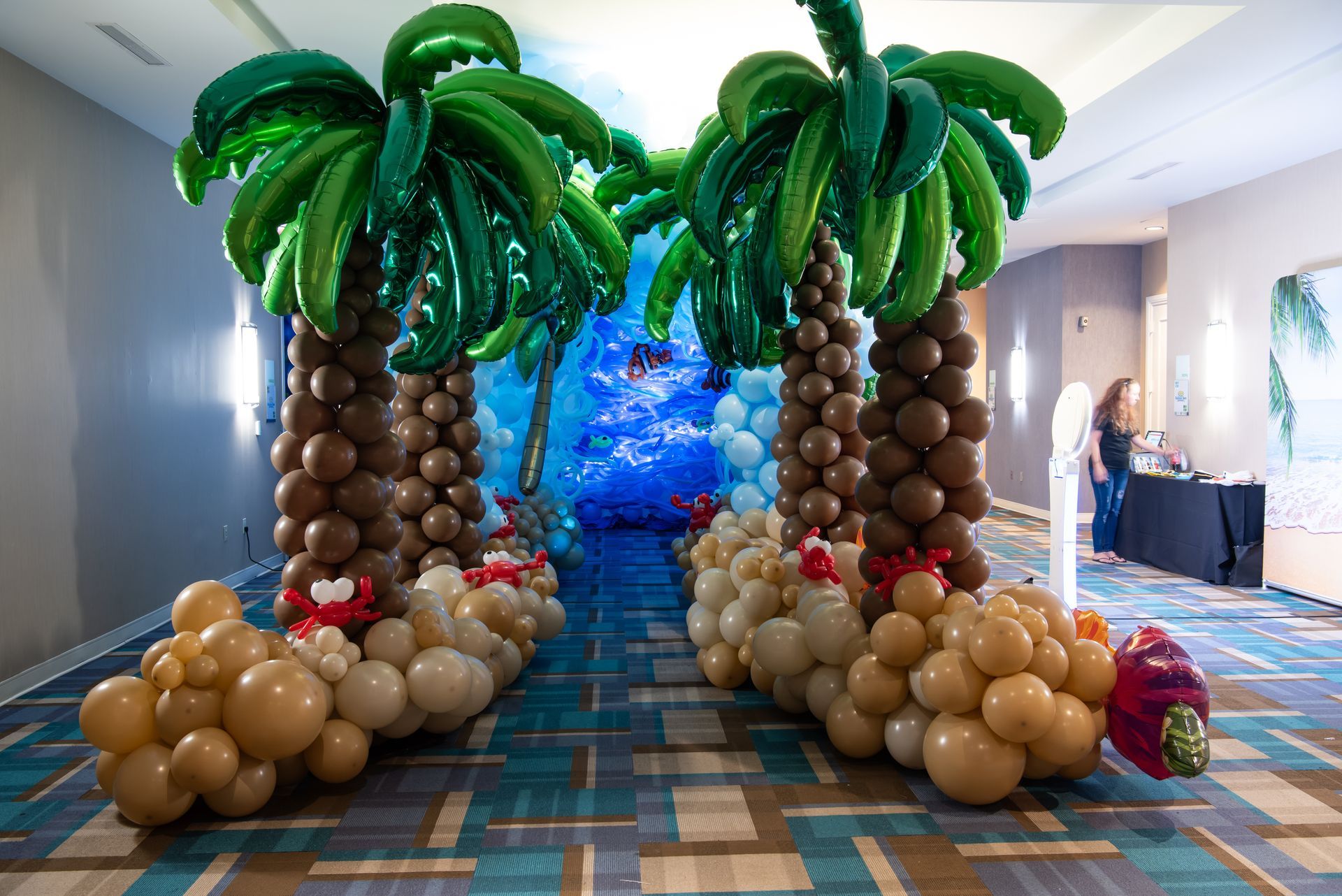 A hallway decorated with palm trees made out of balloons.