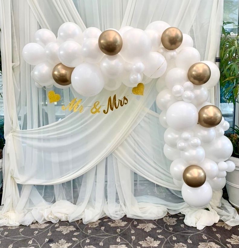 A white curtain with balloons and a sign that says mr. and mrs.