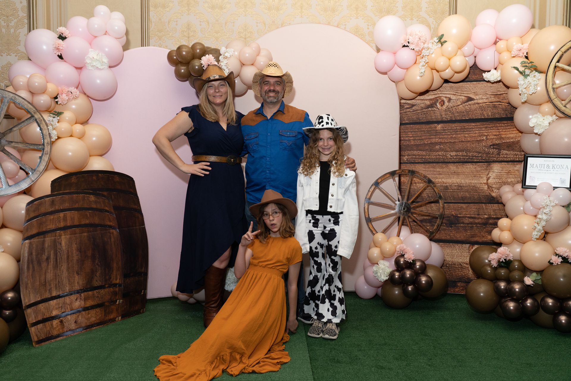 A family is posing for a picture in front of a wall decorated with balloons.