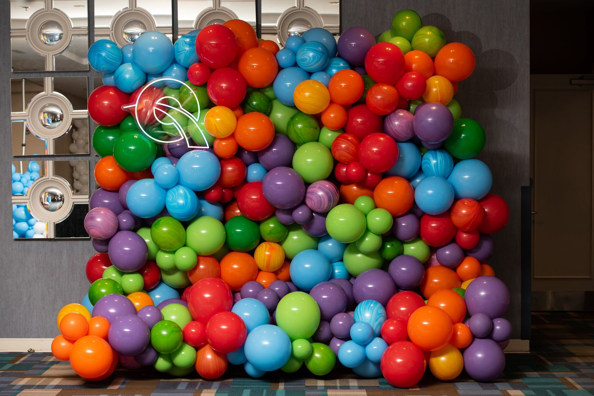 A wall of colorful balloons is sitting on the floor.