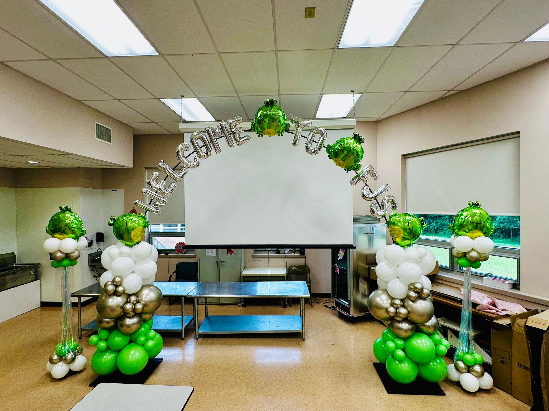 A room filled with balloons and a projector screen.