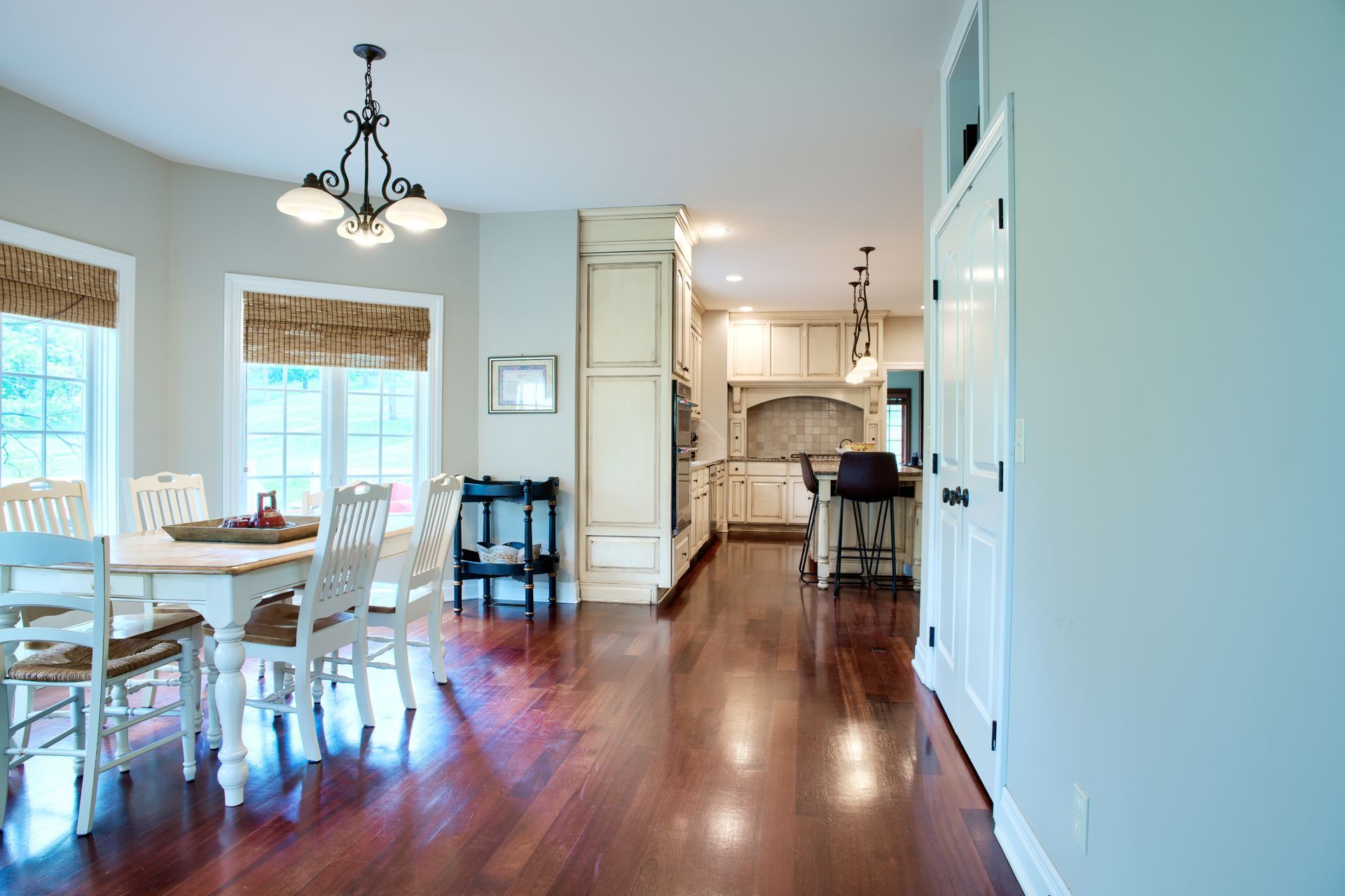 A dining room with a table and chairs and a kitchen in the background.