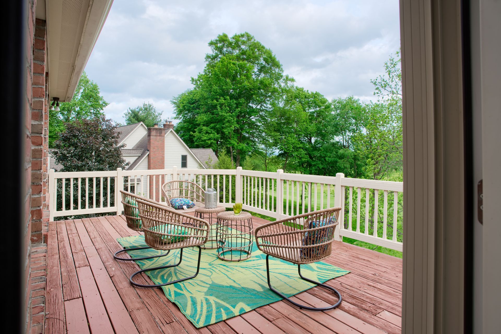 A wooden deck with chairs , a table and a rug.