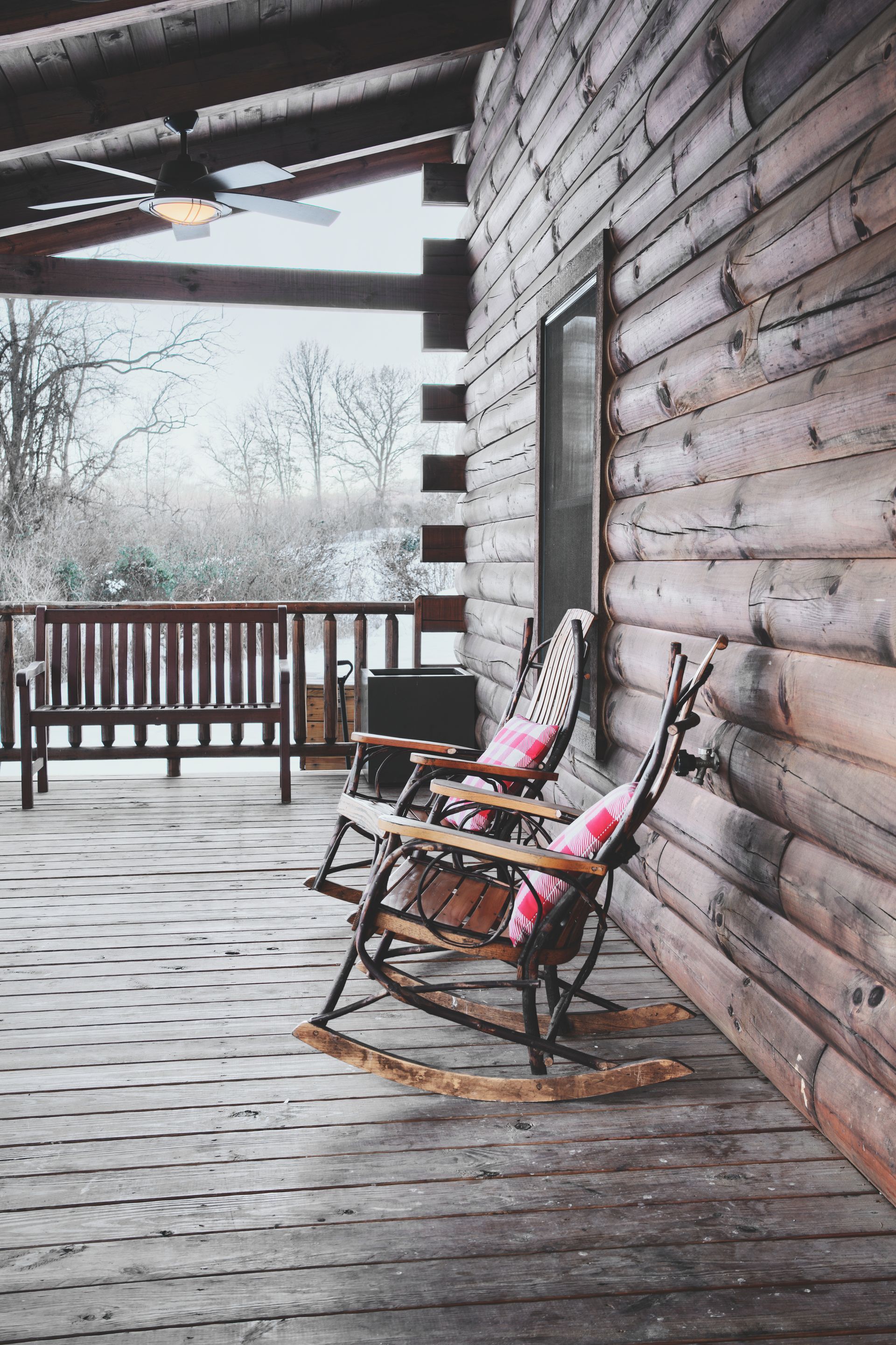 Two rocking chairs are sitting on a porch of a log cabin in hocking hills.