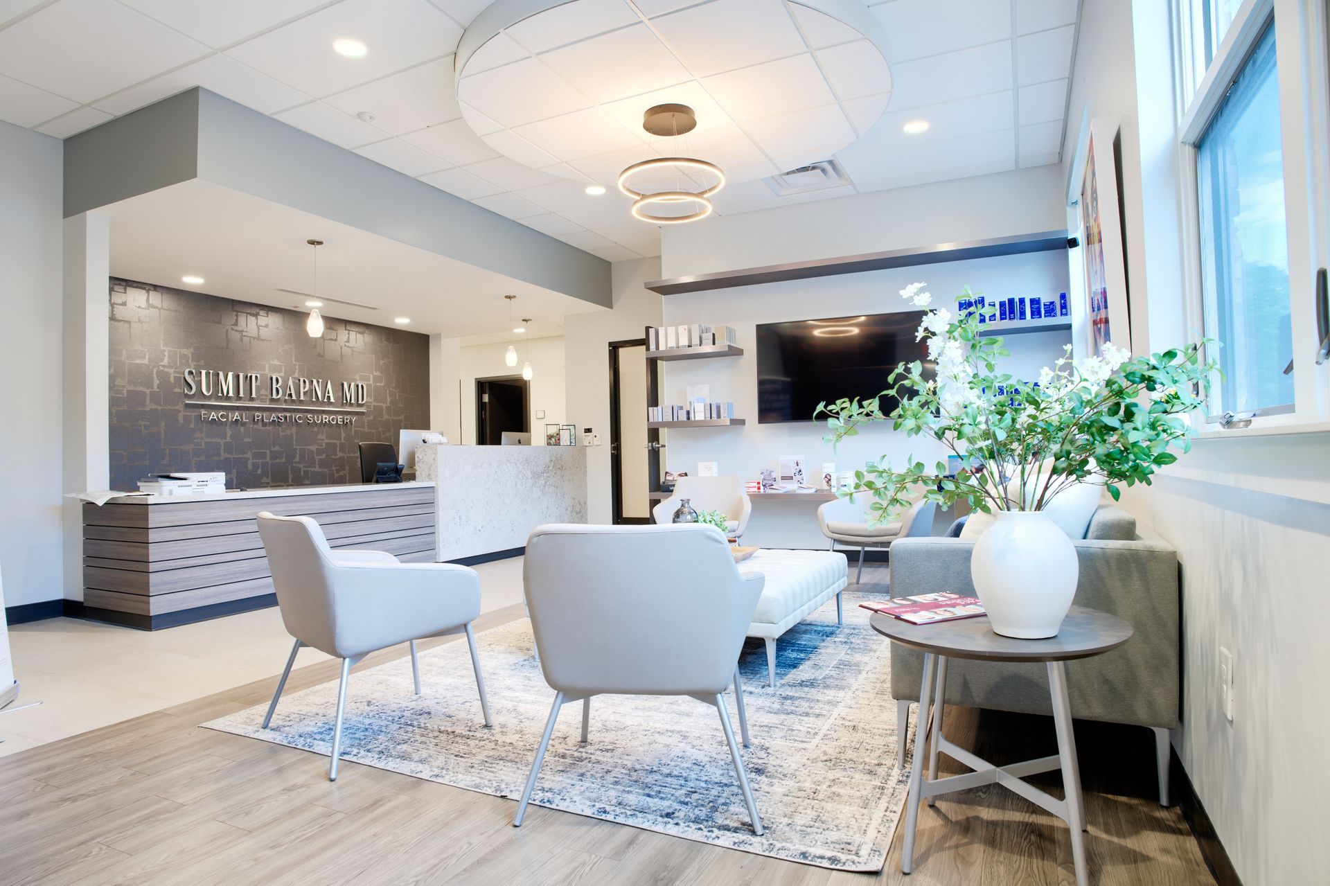A waiting room with chairs , a couch , a table and a television.