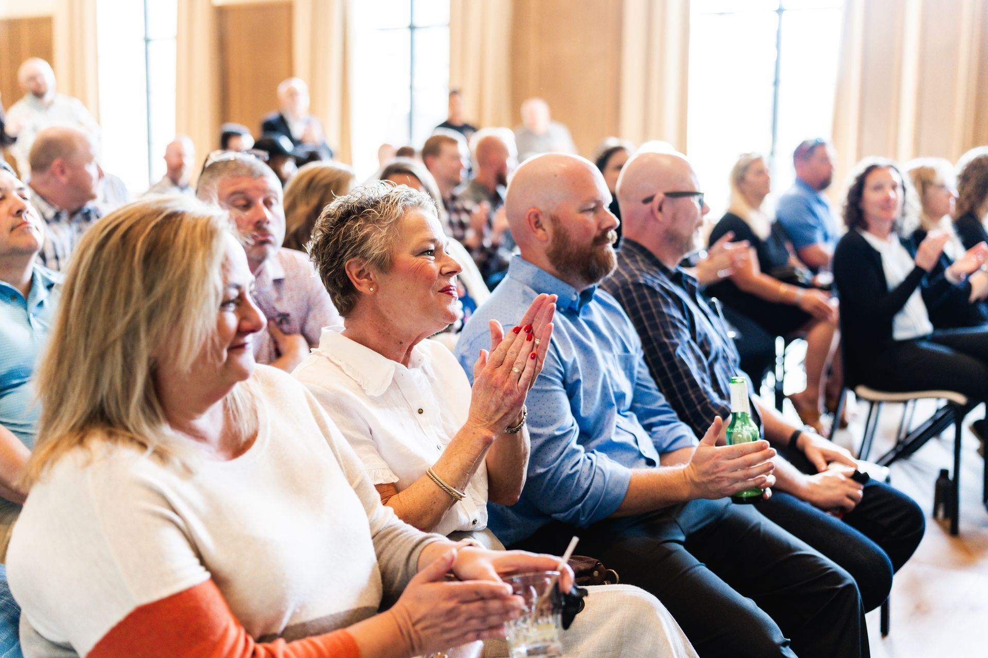 A group of people are sitting in a room clapping their hands.