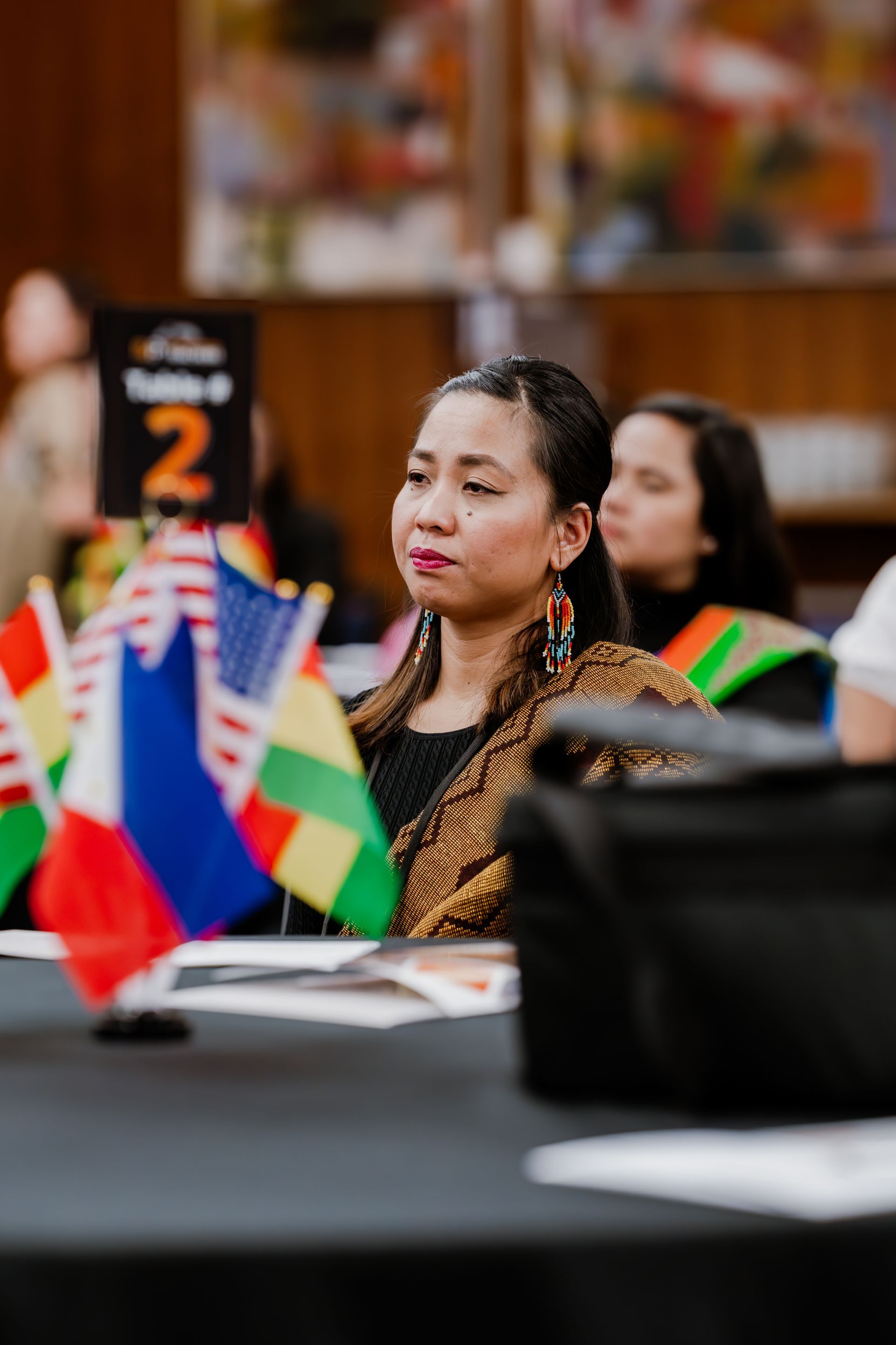 A person sits at a table with miniature international flags and a 