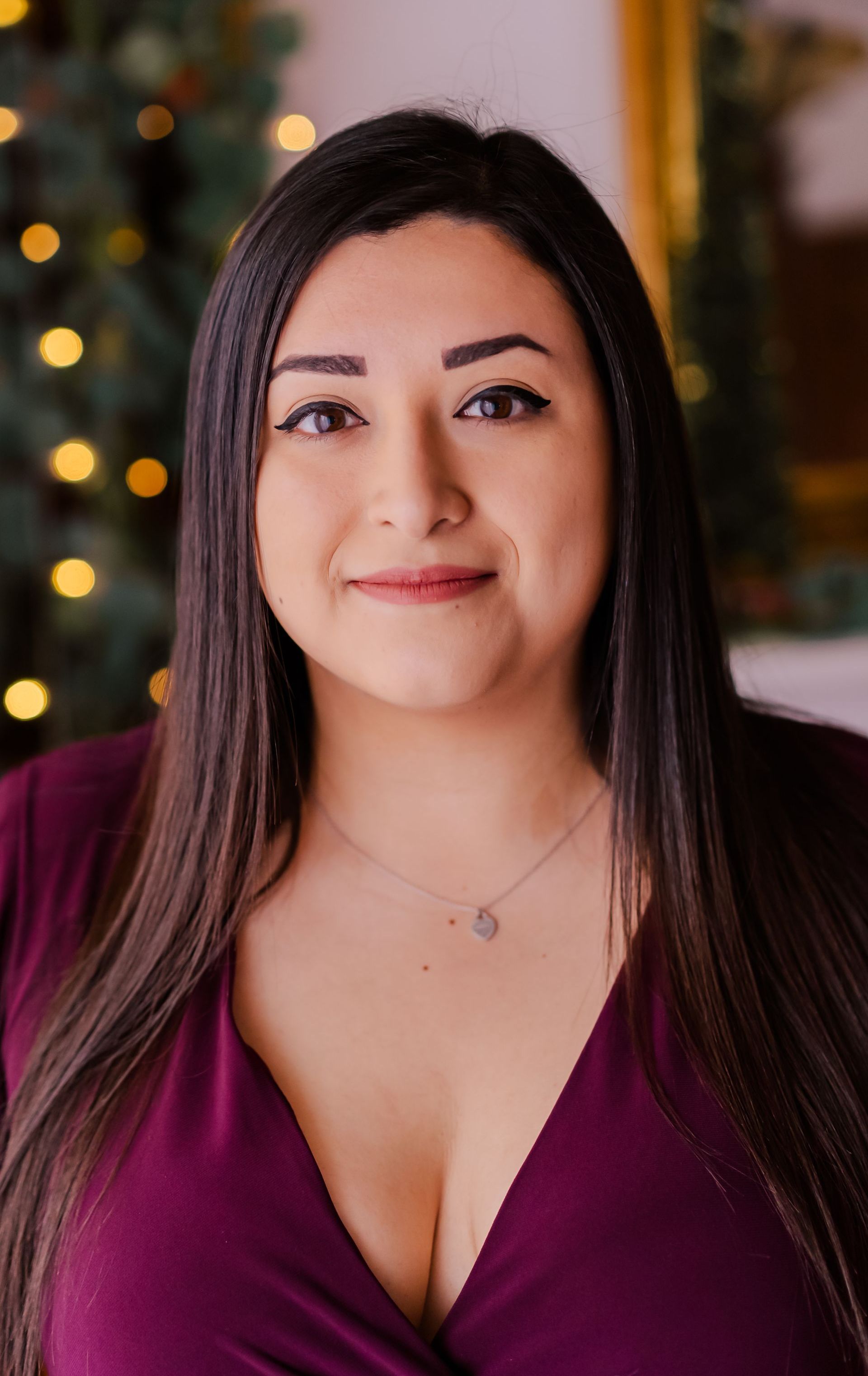 a woman in a purple dress is standing in front of a christmas tree .