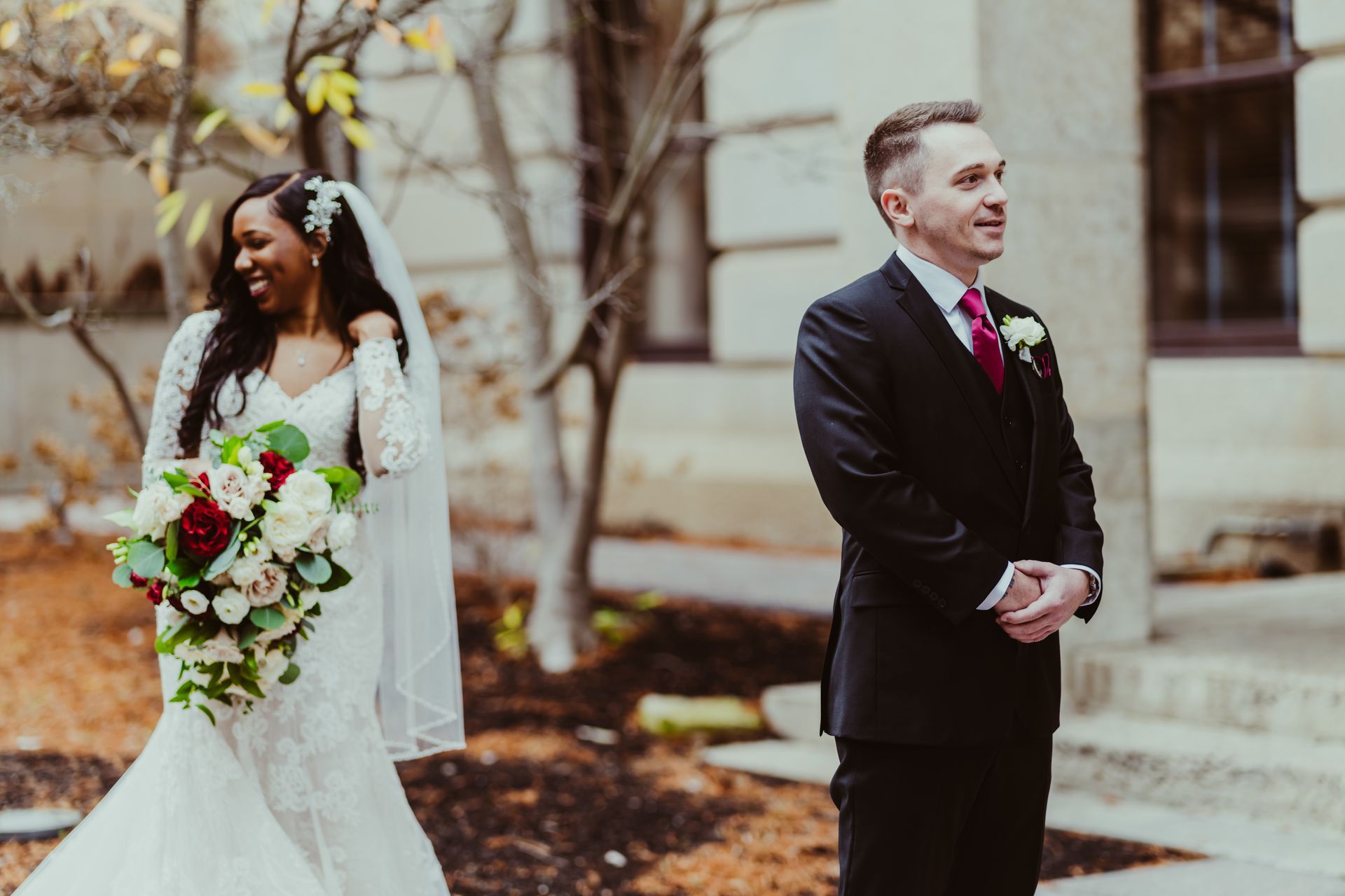 A bride and groom are standing next to each other in front of a building.