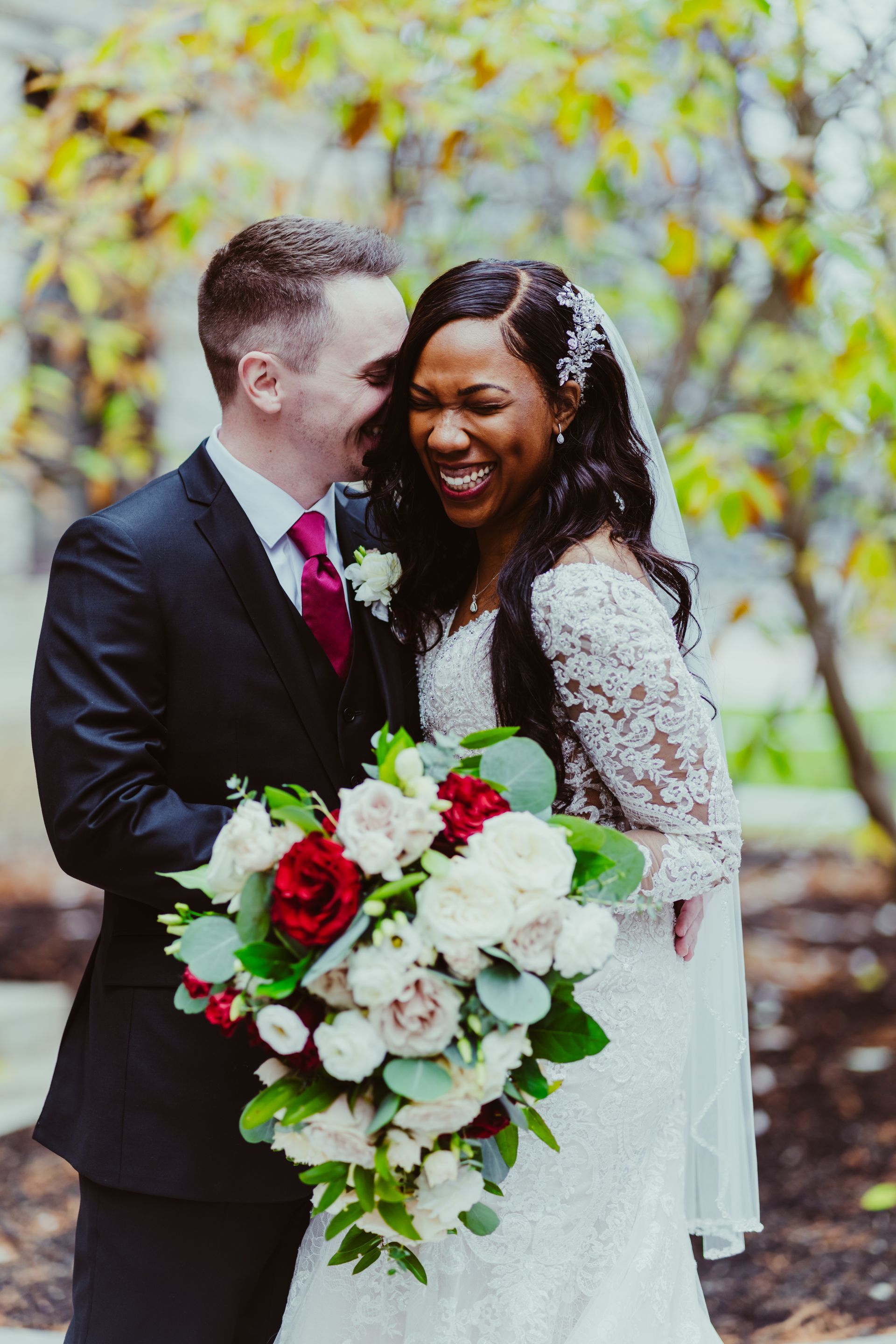A bride and groom are posing for a picture and the bride is holding a bouquet of flowers.
