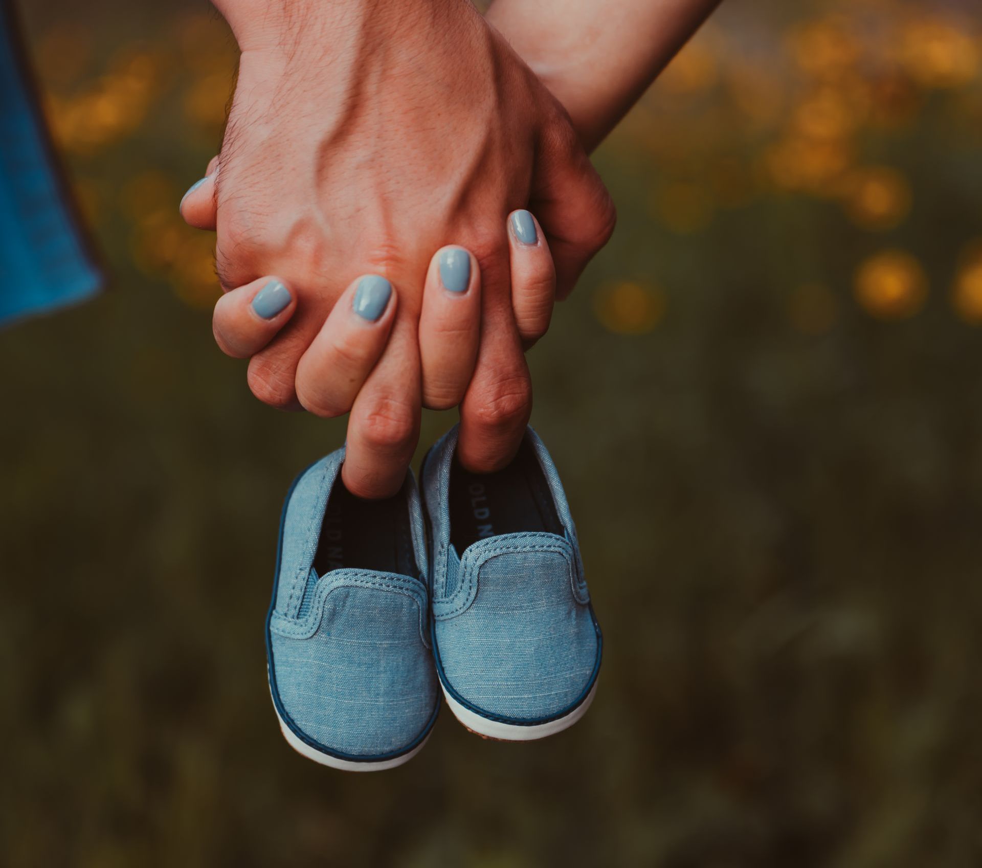 a man and a woman are holding a pair of baby shoes in their hands .