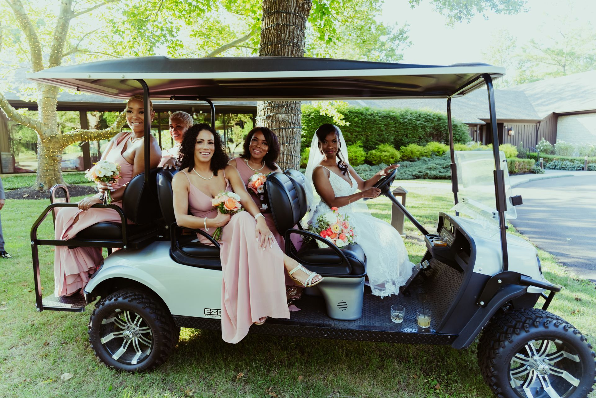 A bride and her bridesmaids are sitting in a golf cart.