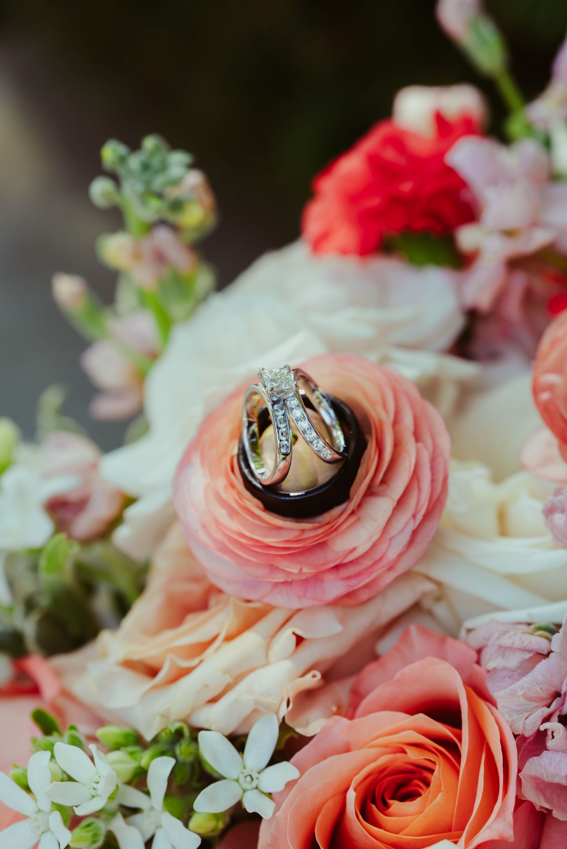The wedding rings are sitting on top of a bouquet of flowers.