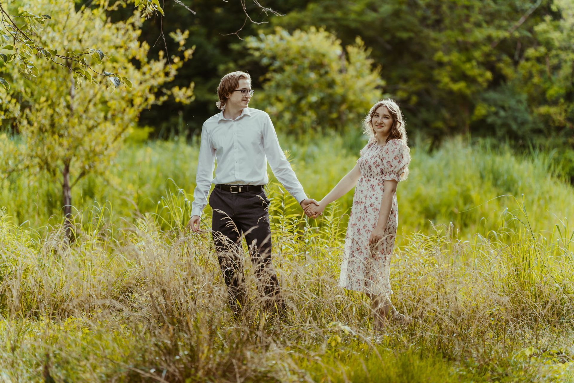 A man and a woman are holding hands in a field.