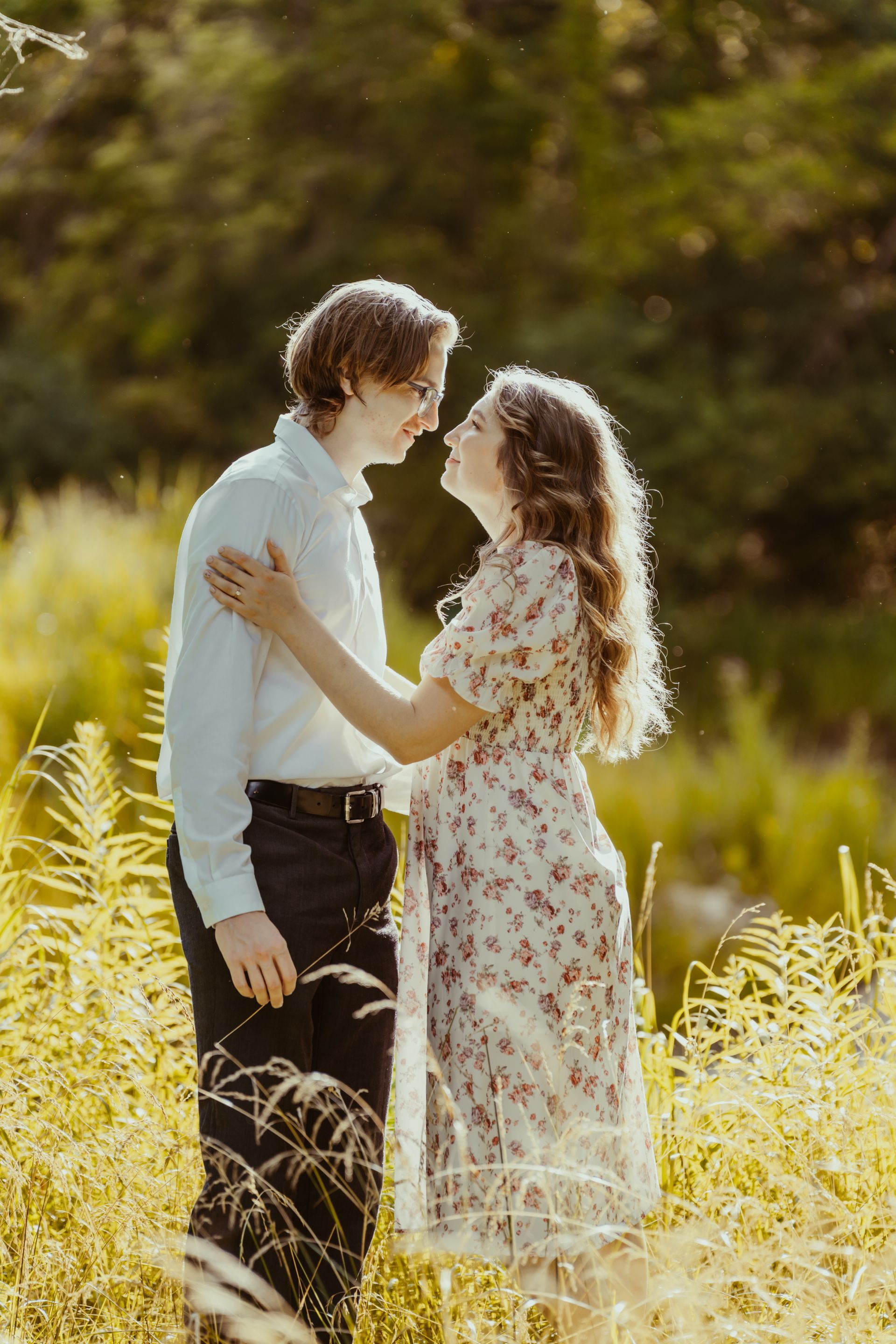A man and a woman are standing in a field looking at each other.