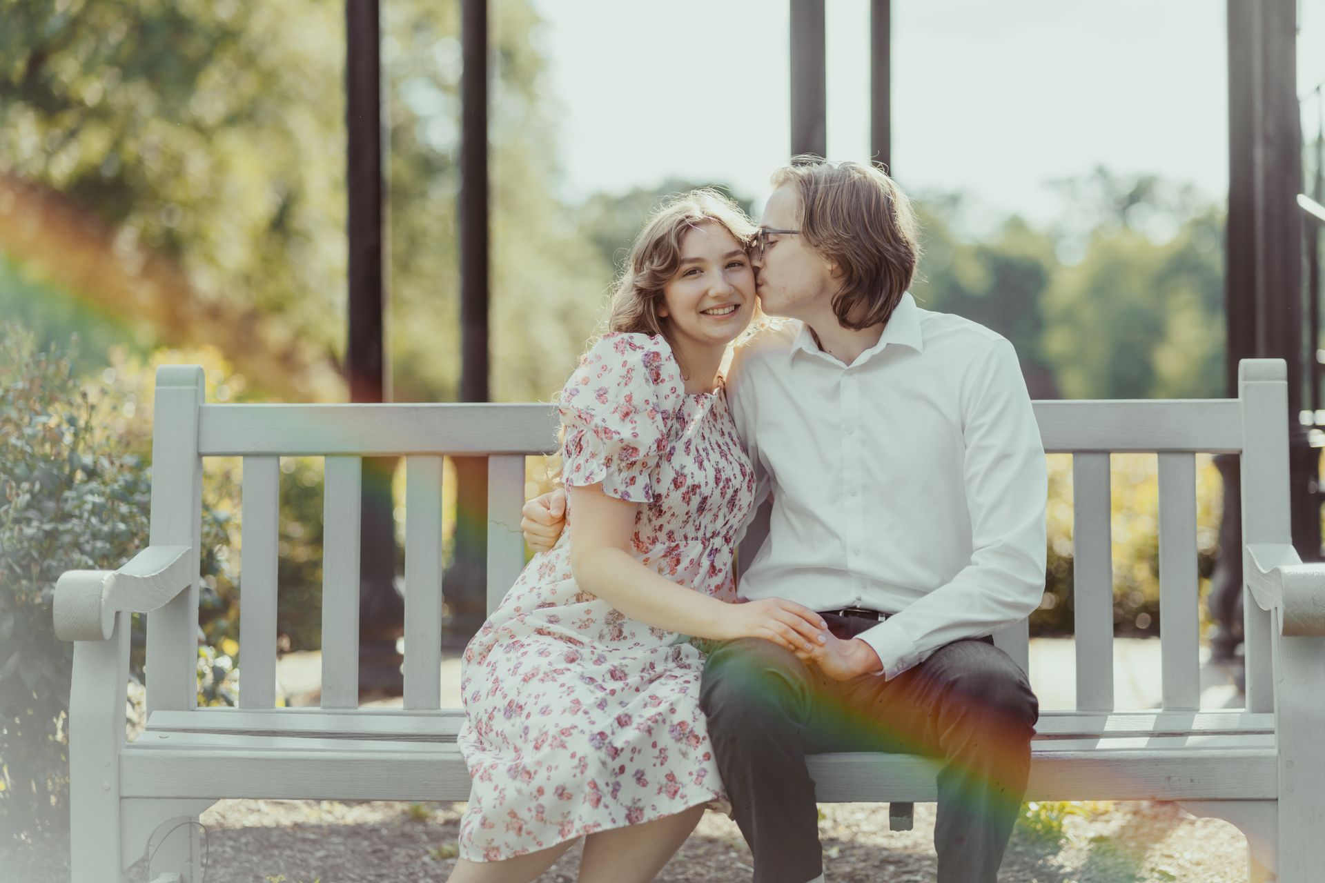 A man is kissing a woman on the cheek while sitting on a bench.