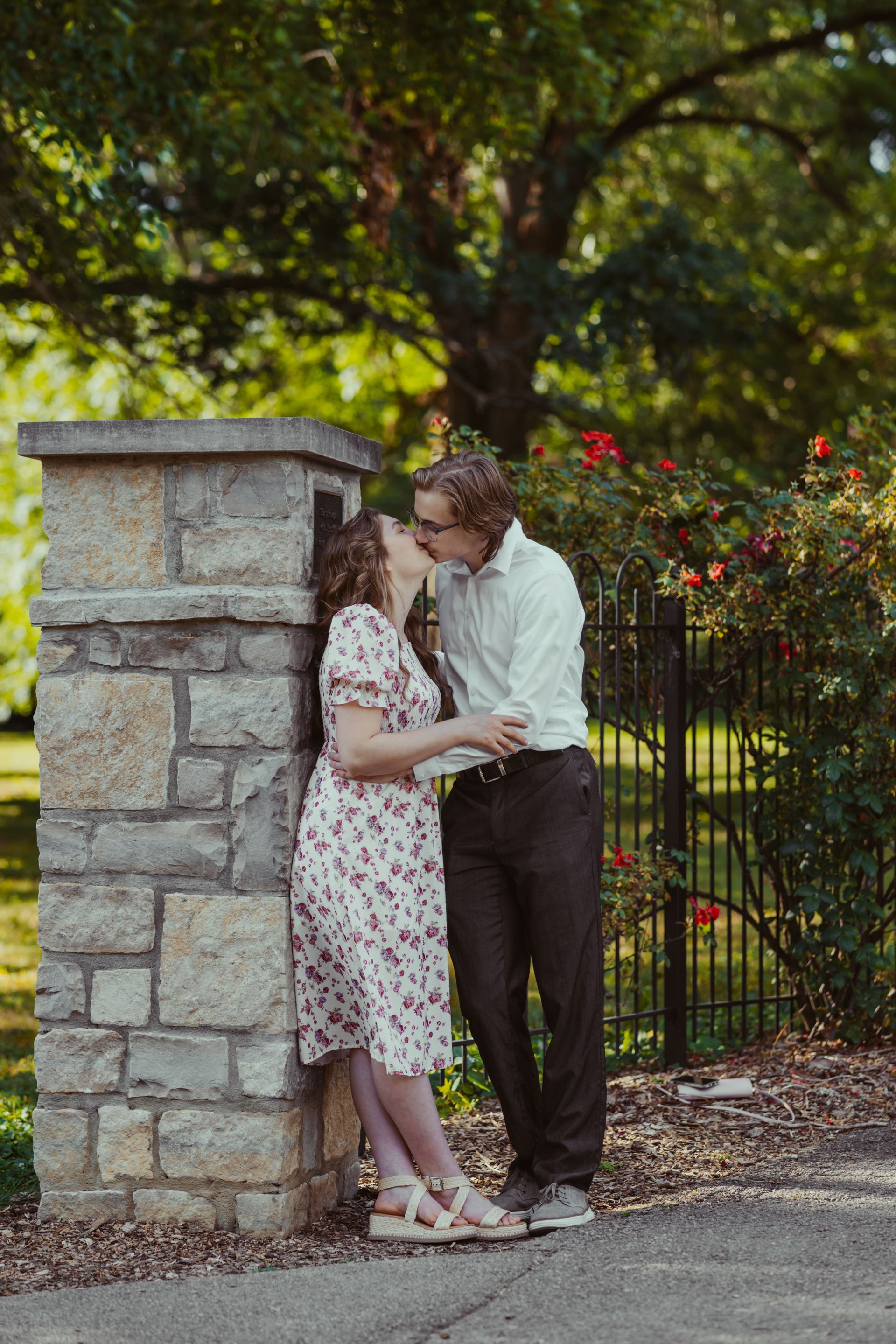 A man and a woman are kissing against a stone wall.
