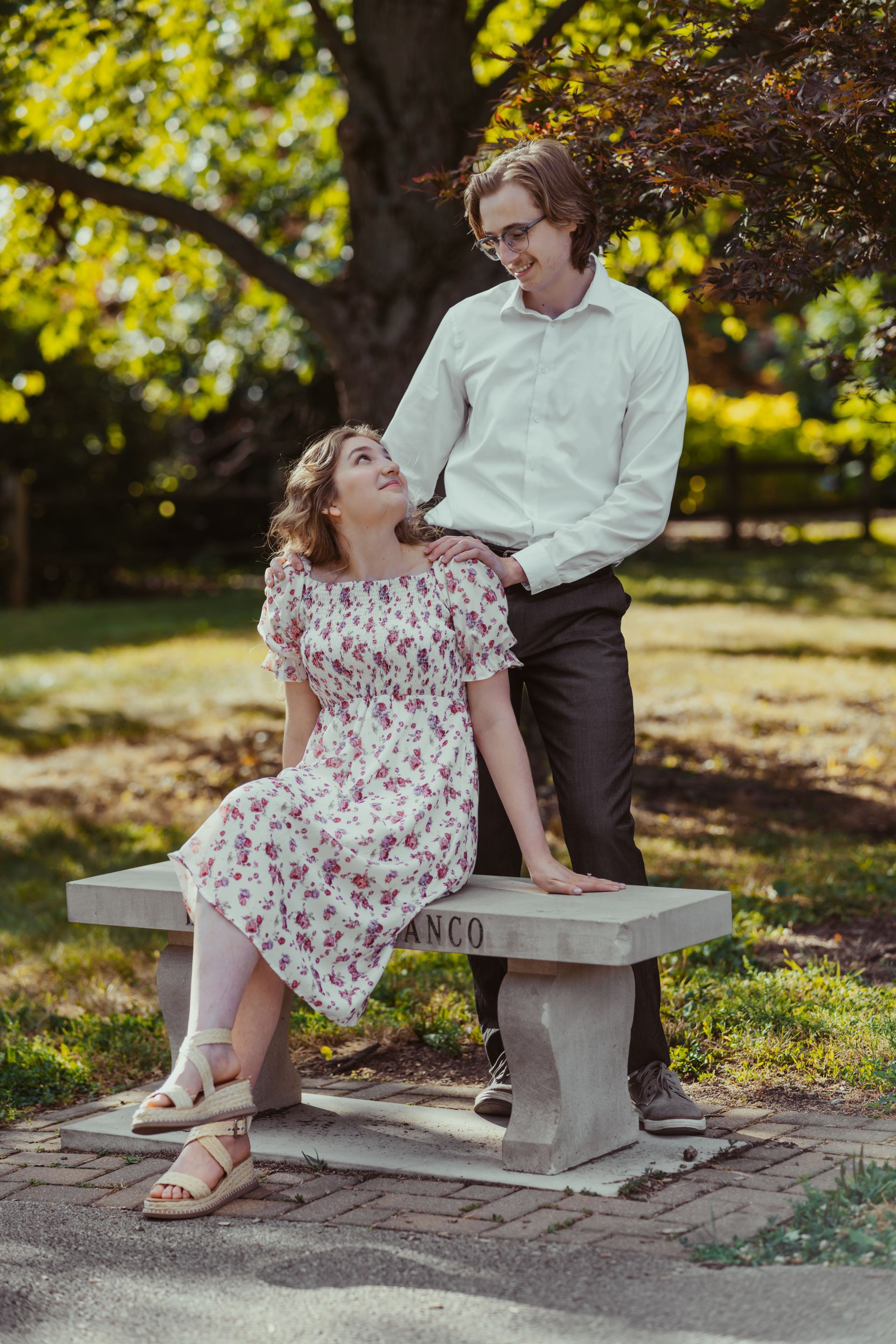 A man and a woman are sitting on a bench in a park.