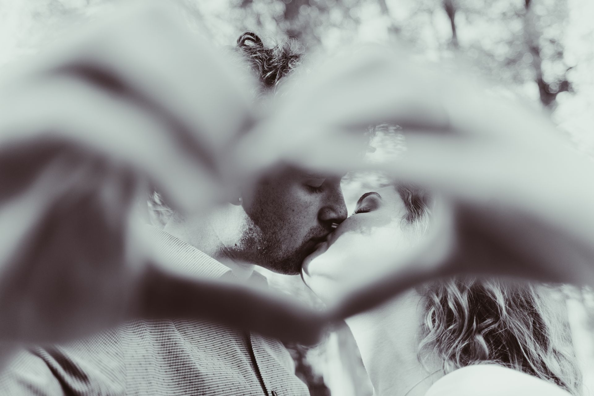Couple kissing, hands forming heart shape around them.