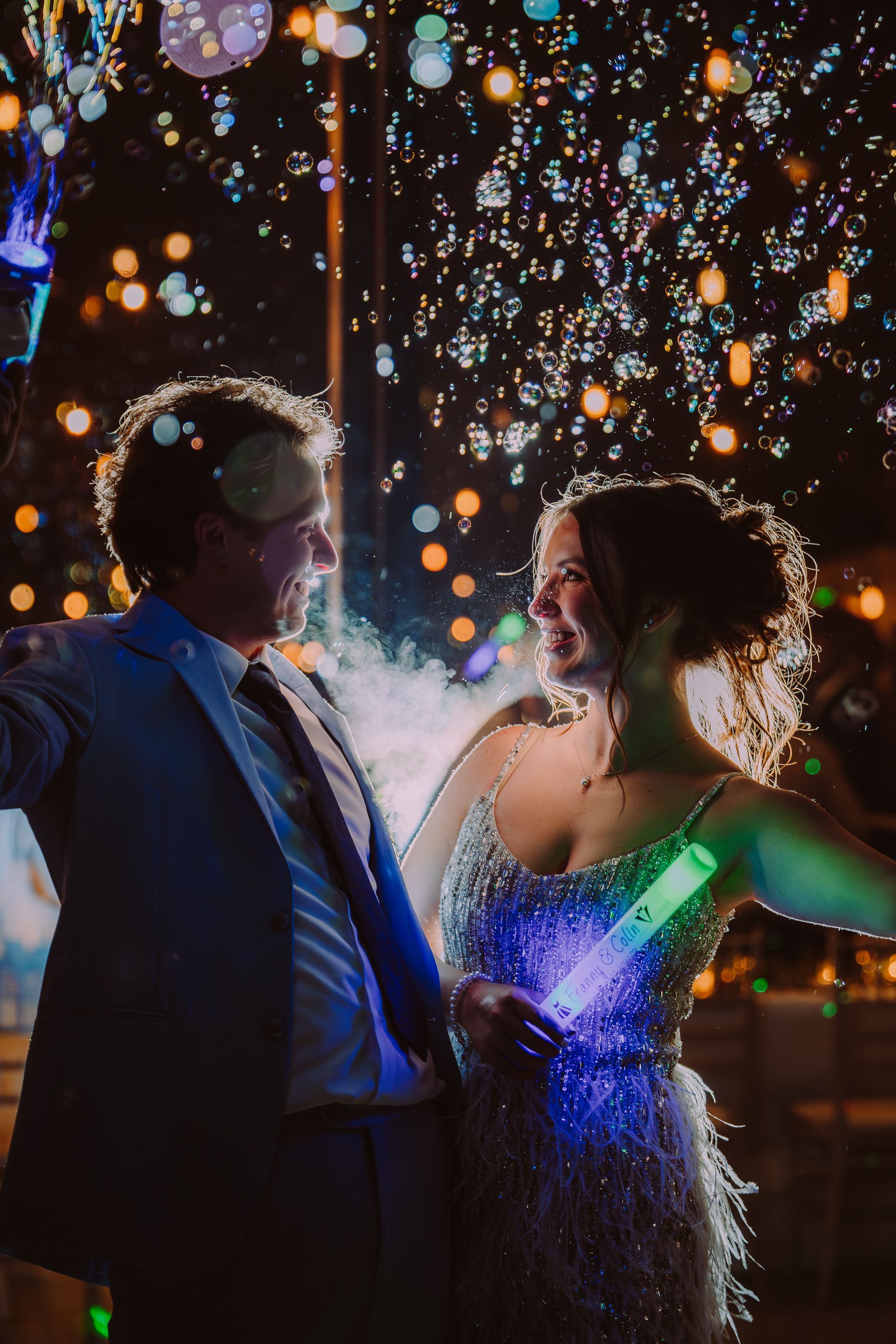 Couple celebrates with confetti and glow sticks at night.