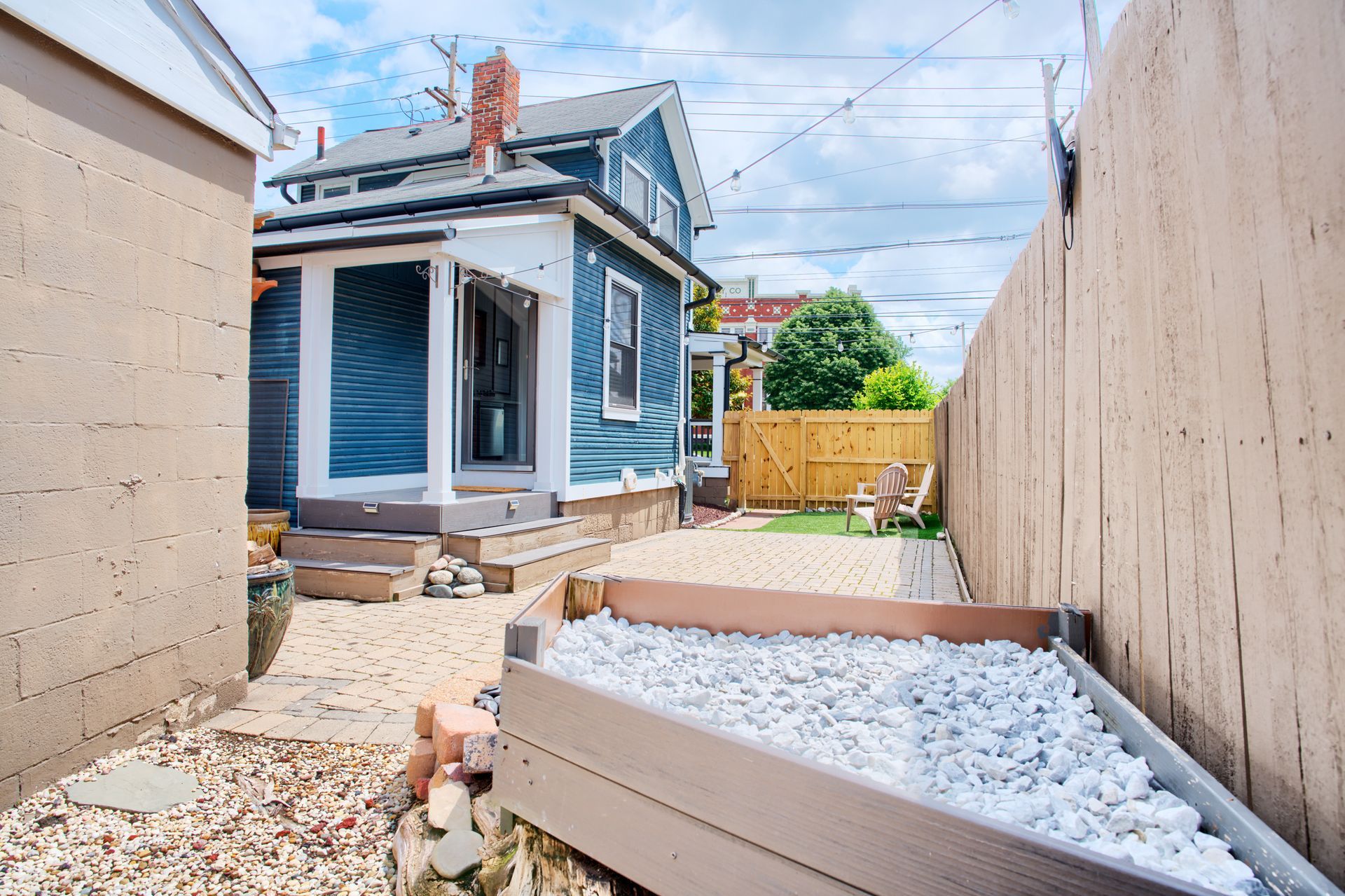 A backyard with a blue house and a wooden fence