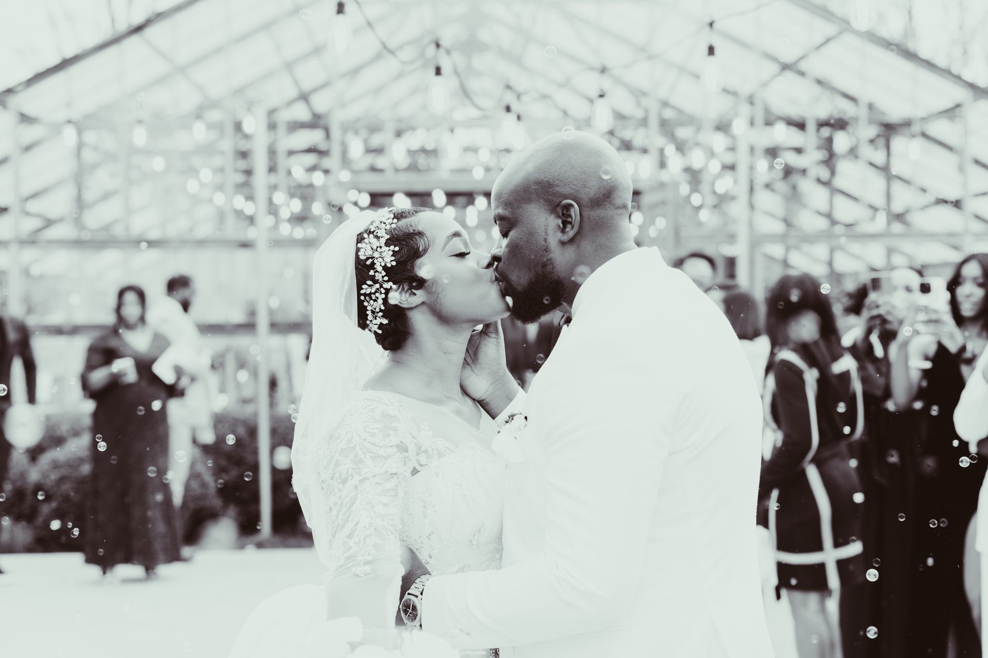 A black and white photo of a bride and groom kissing at their wedding reception.