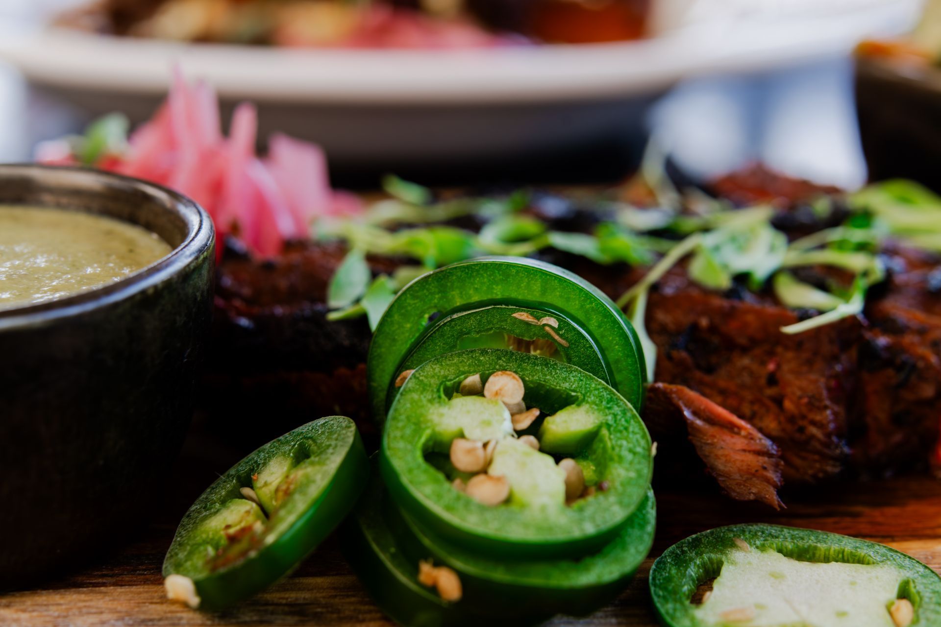 A close up of a plate of food with jalapenos and sauce on a table.