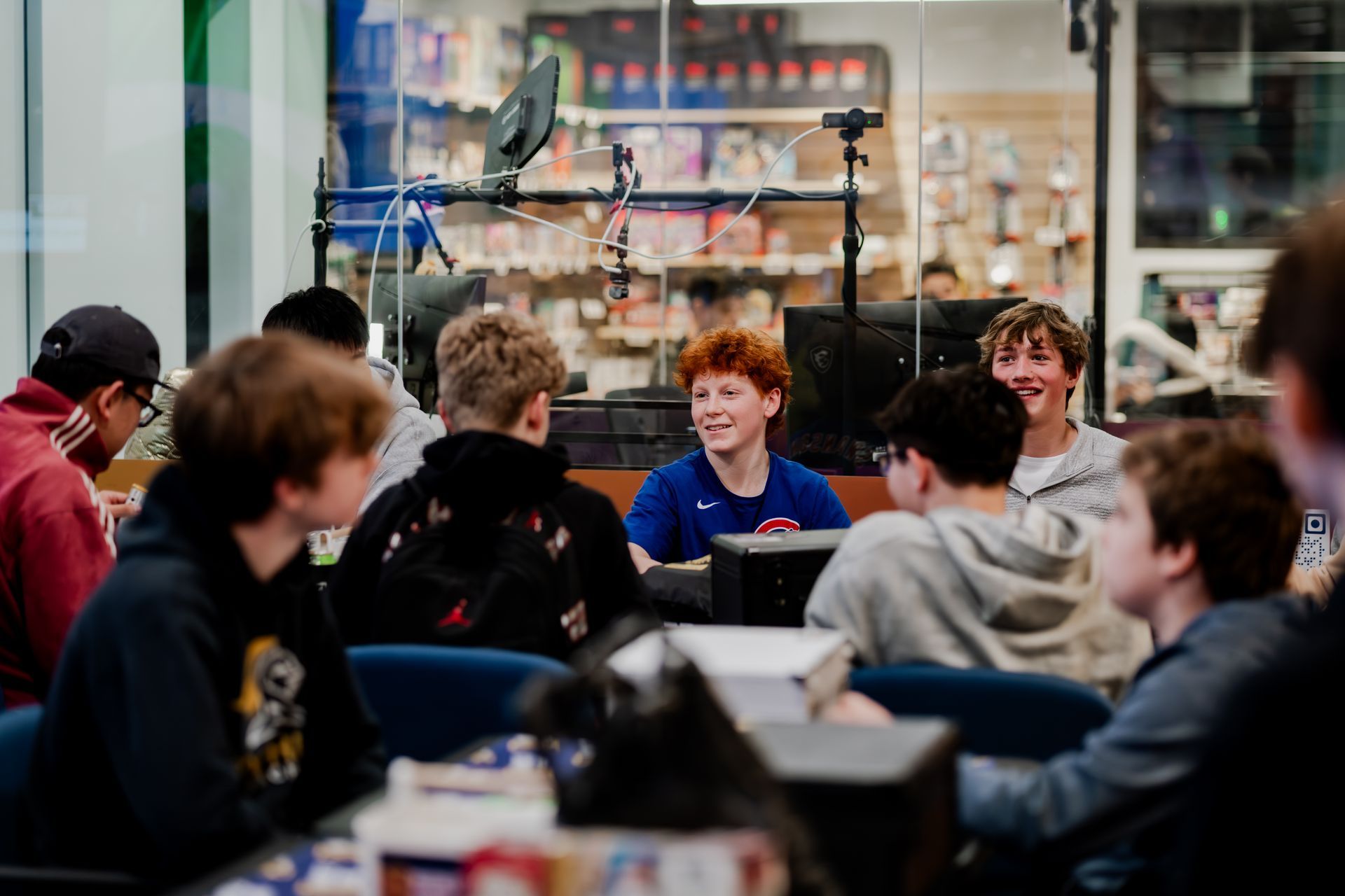Group of young people sitting around a table, some smiling. wall.Midwest Card | Event Photography
