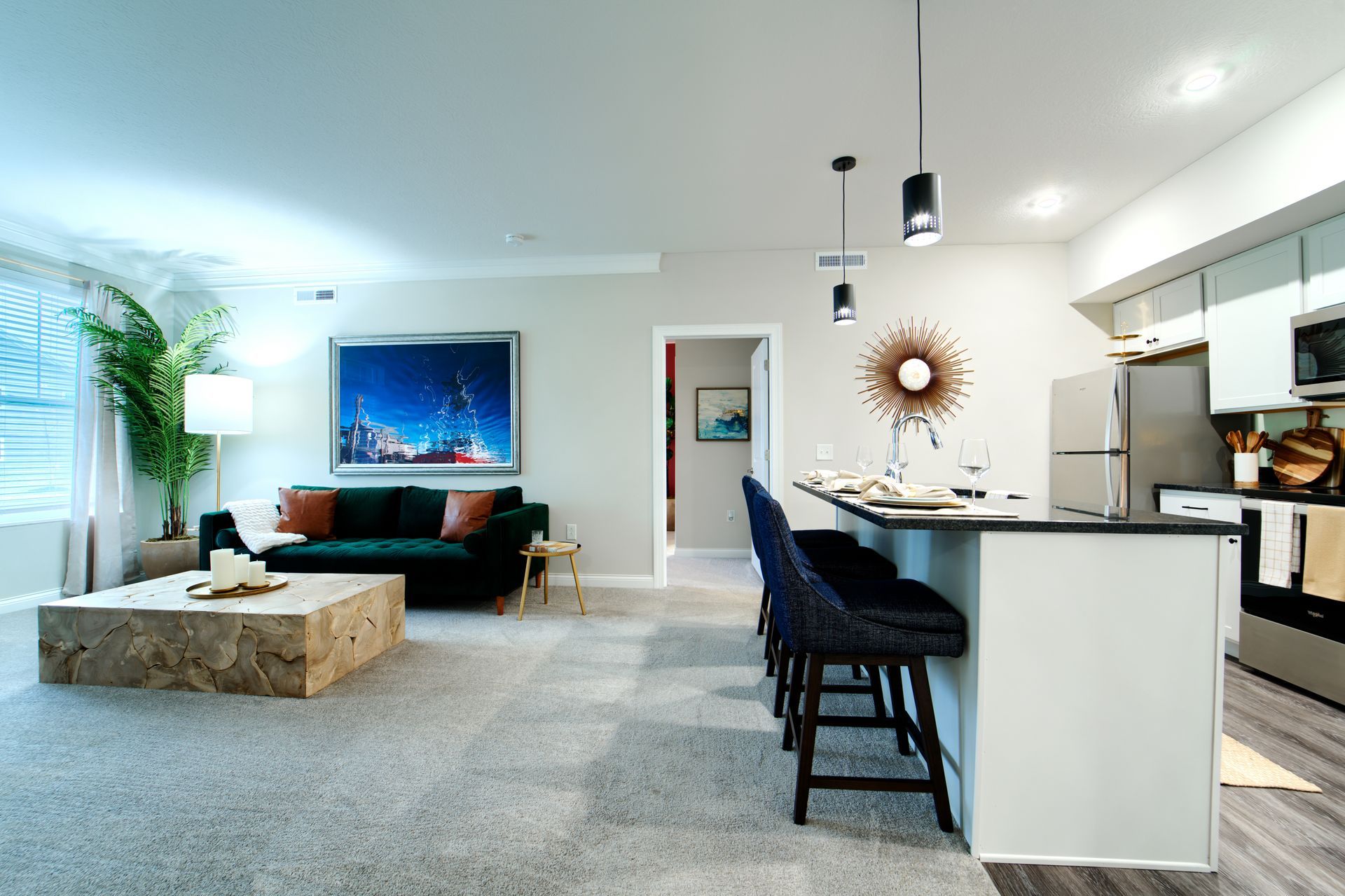 A living room with a couch , table , chairs and a kitchen.