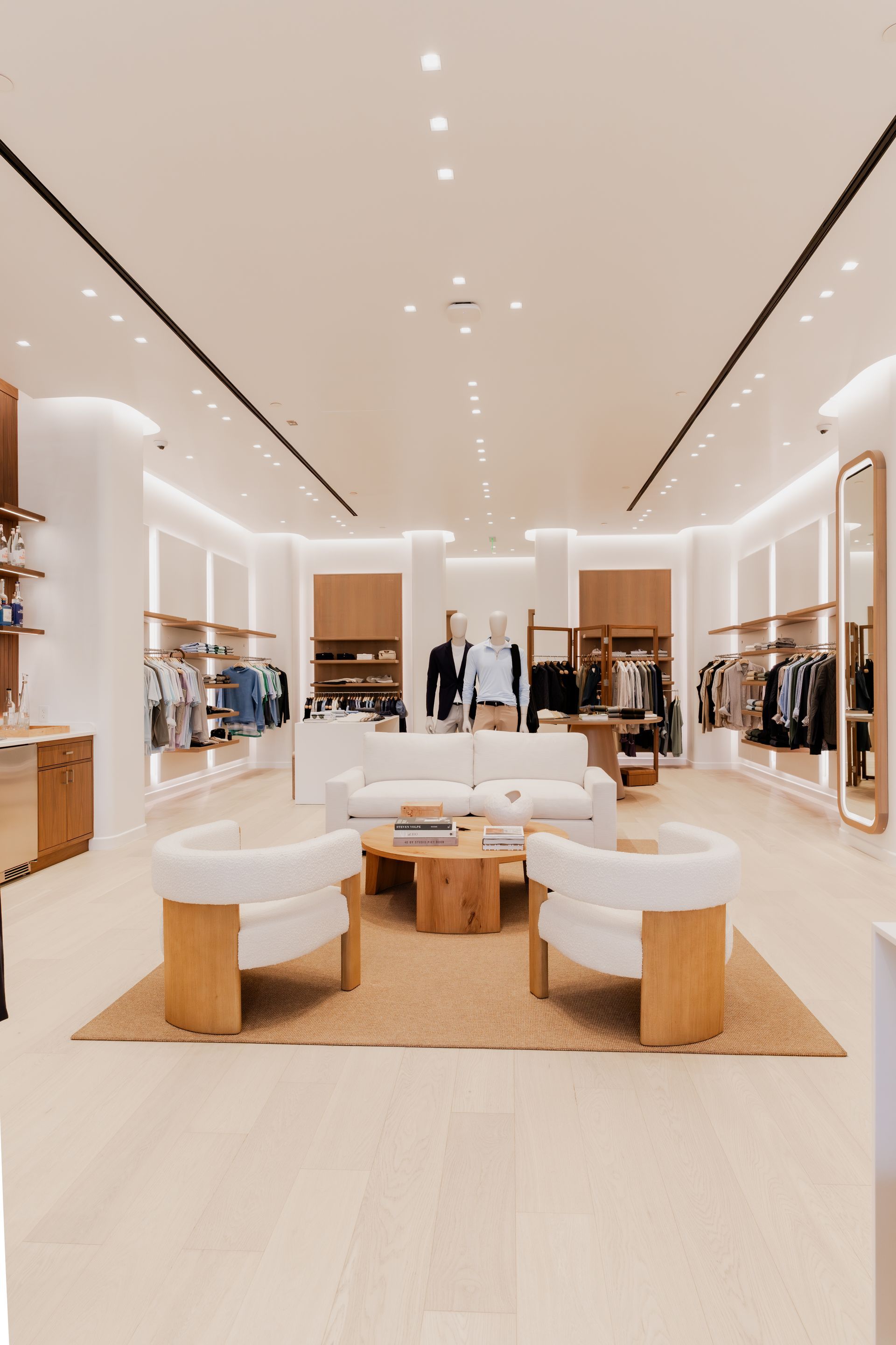 Bright retail store interior with seating area and clothing displays.