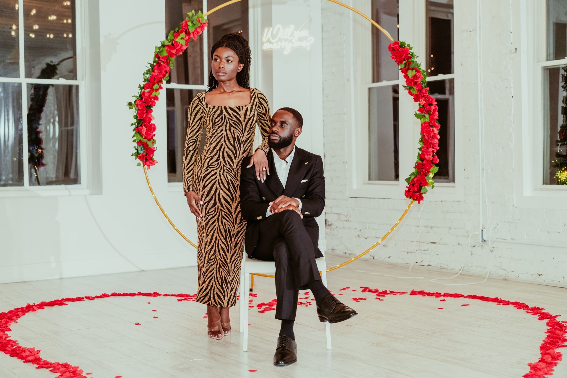 A man is sitting in a chair next to a woman in a leopard print dress.