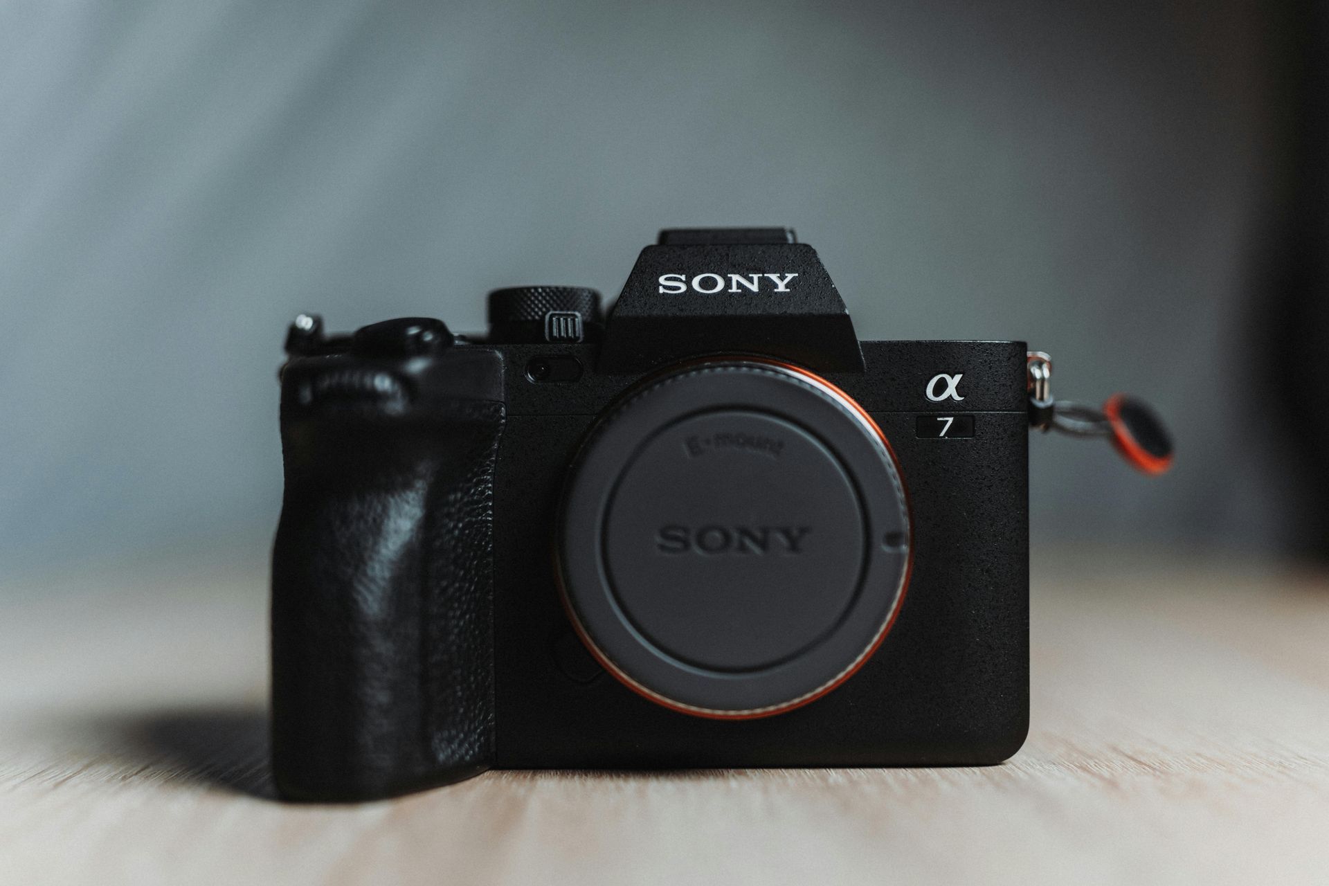 Black Sony Alpha 7 IV camera with lens cap on a wooden surface.
