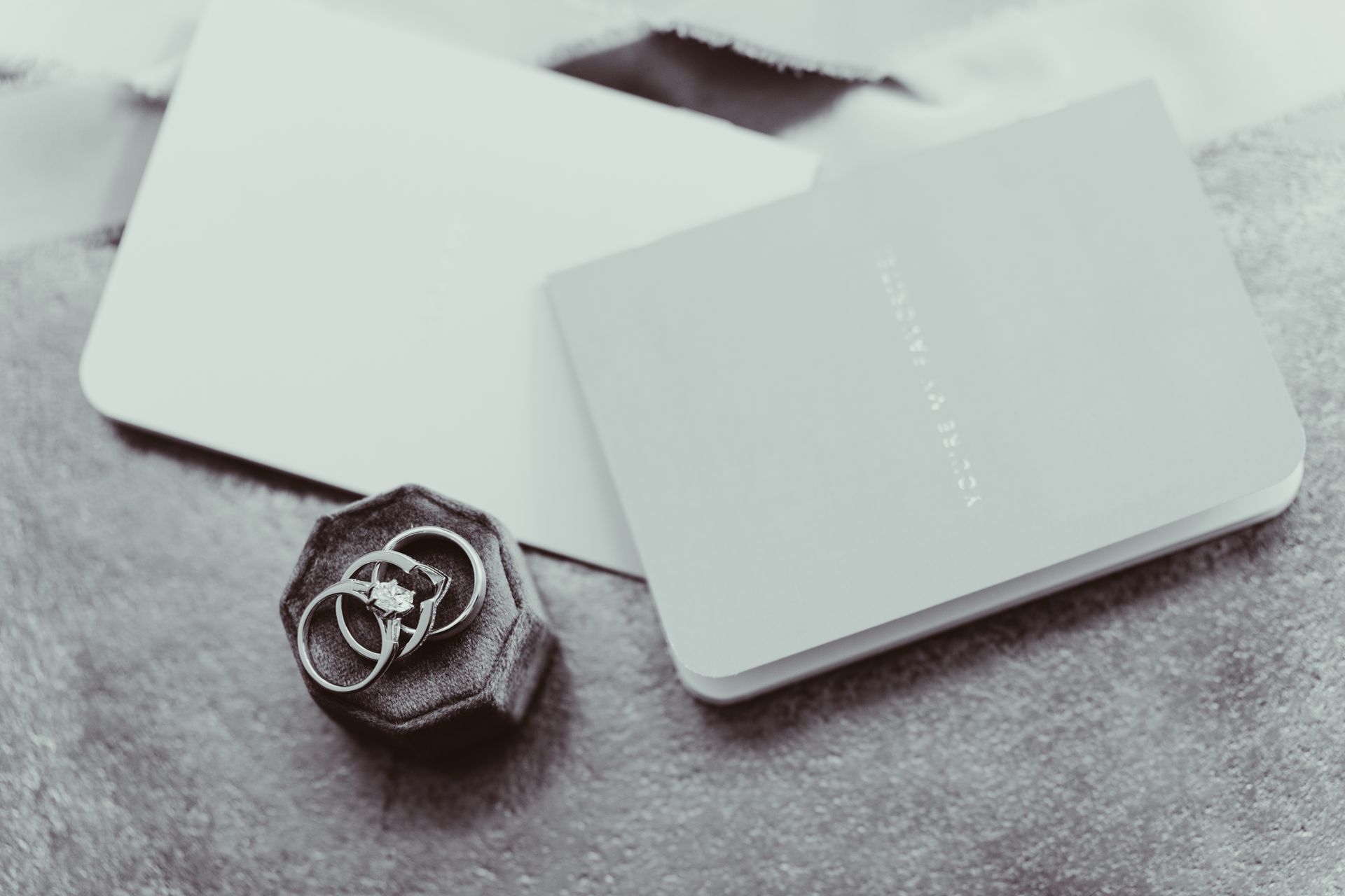 Wedding rings in a velvet box next to a card and a booklet.